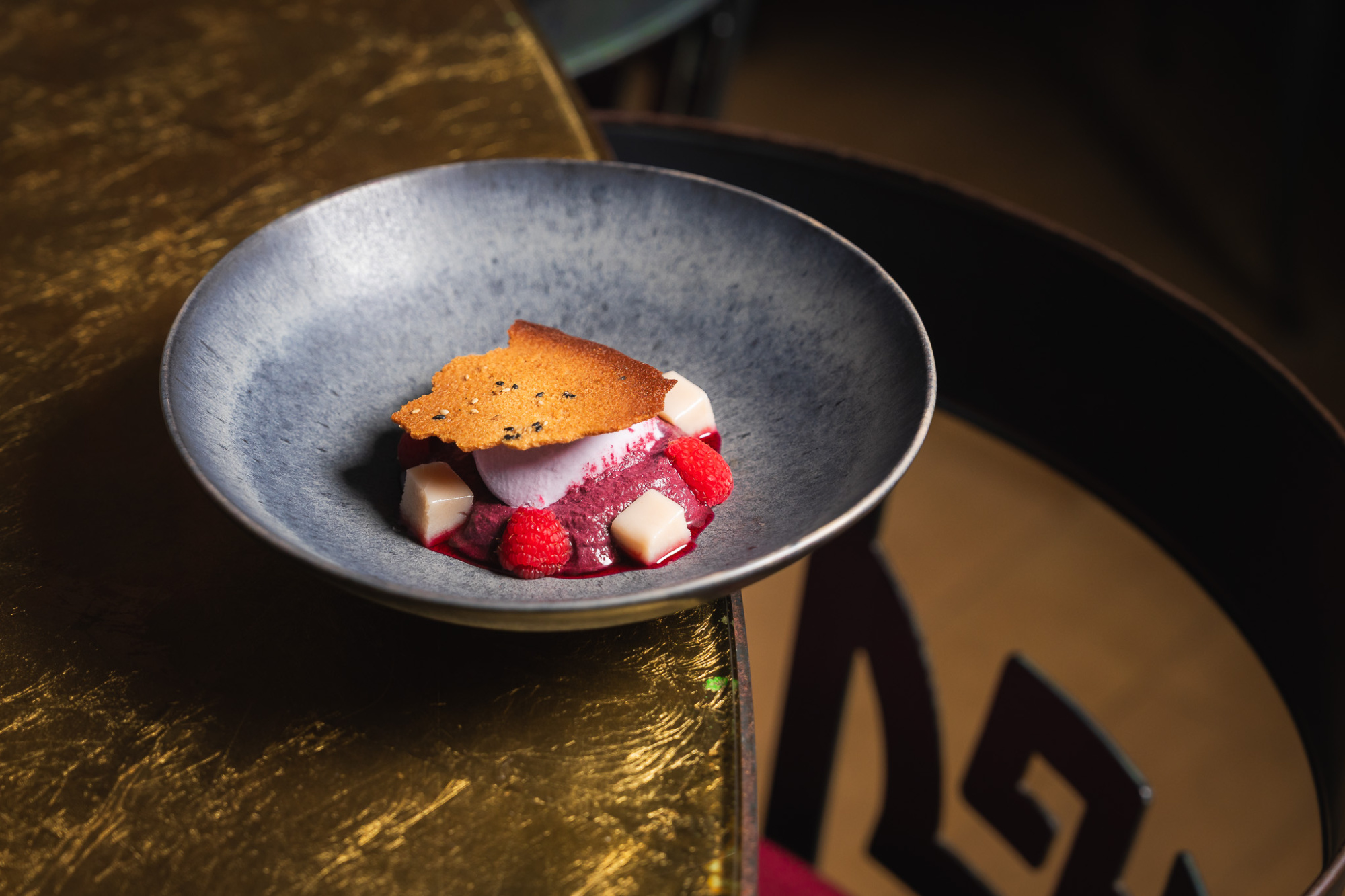 Sirve un plato con cubos de postre y fresas sobre una mesa oscura.