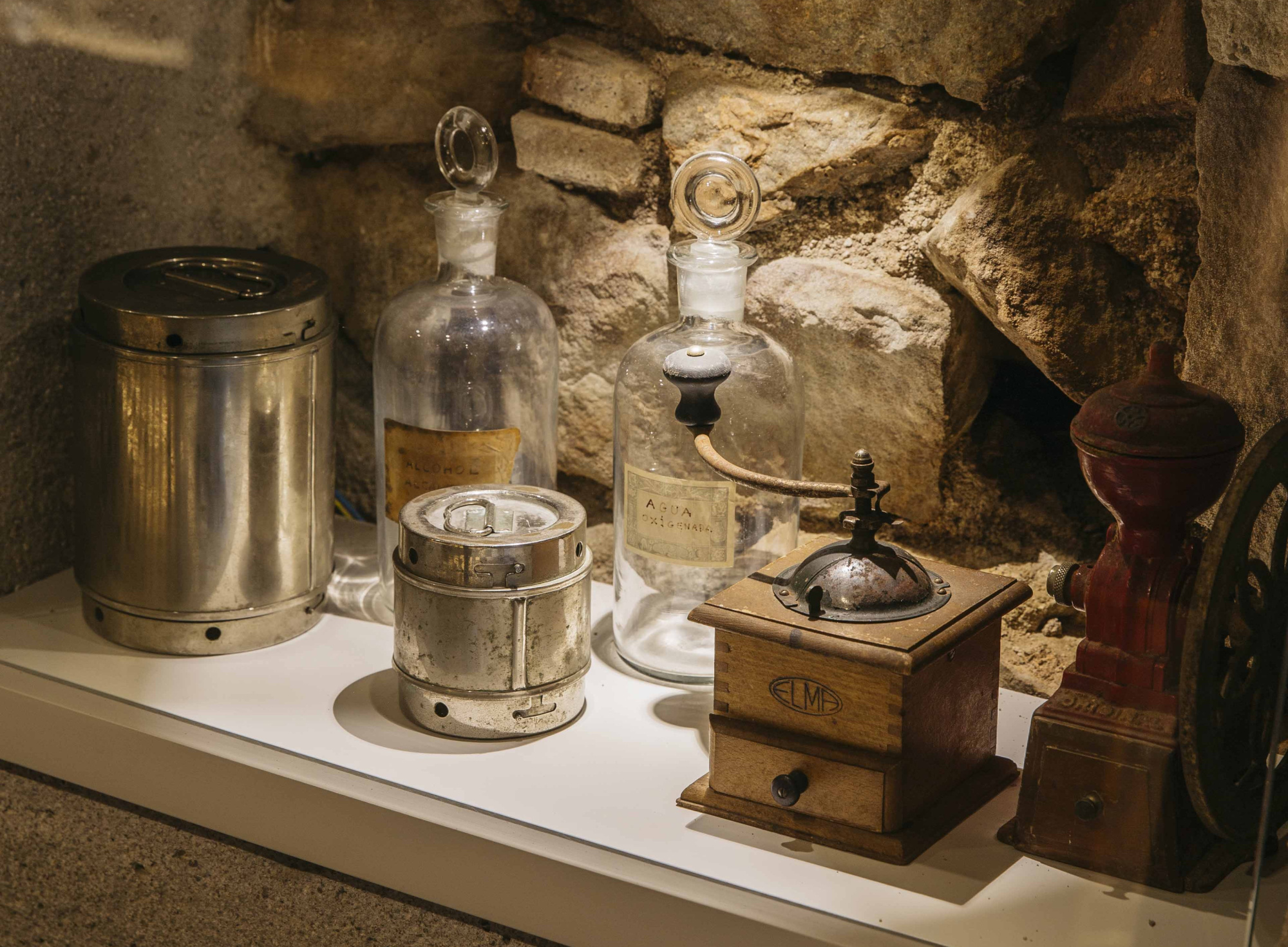 Se observan varios objetos antiguos sobre una mesa en una sala de museo con paredes de piedra.