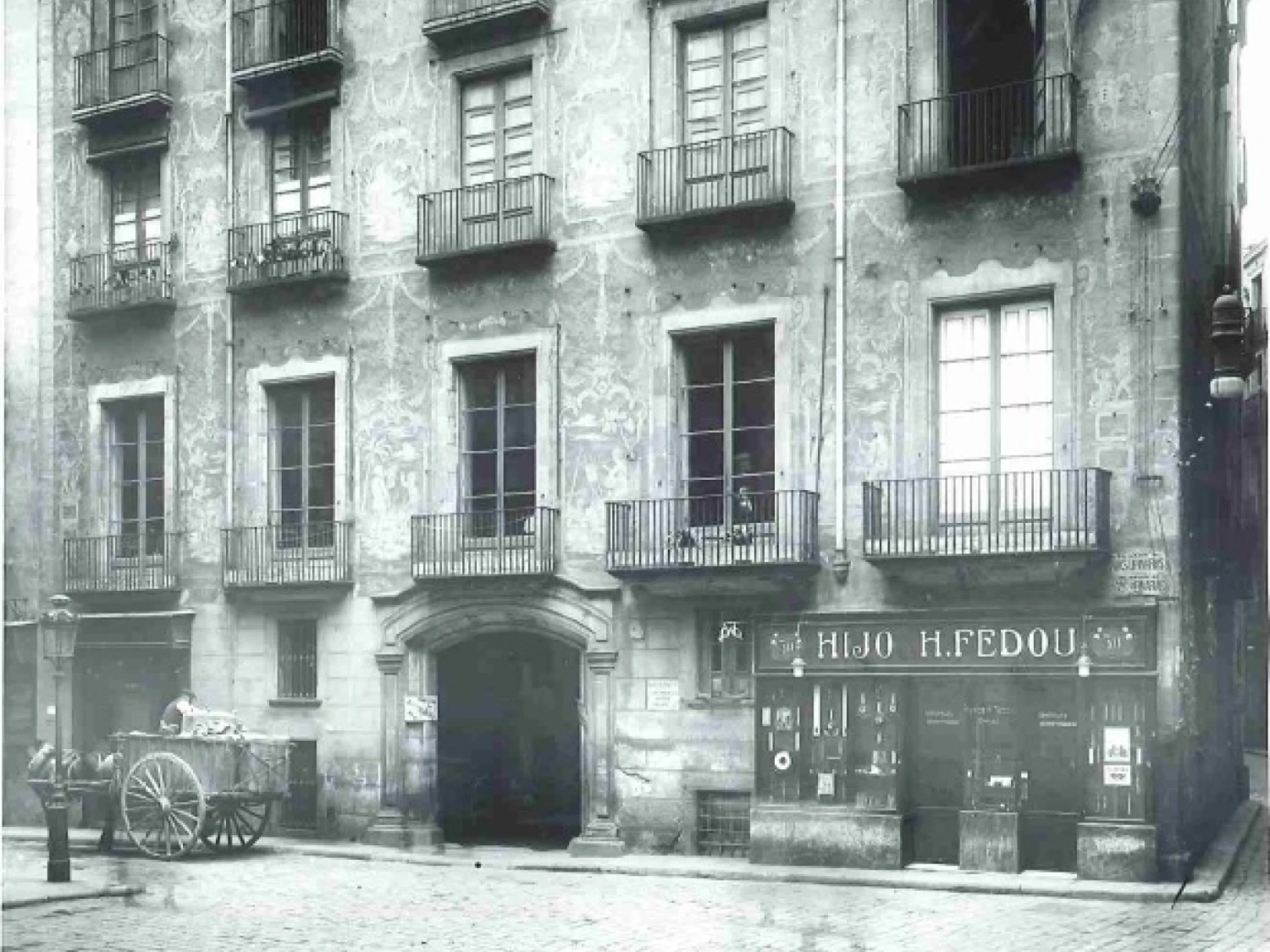 Se ve una fachada de edificio antiguo con balcones y una entrada a nivel de calle.