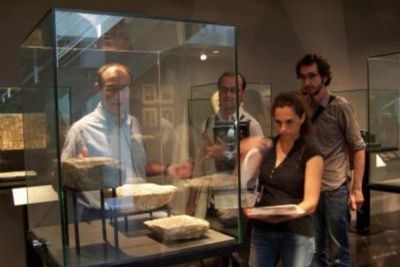 Varias personas se ven frente a una vitrina de vidrio con objetos expuestos en su interior.
