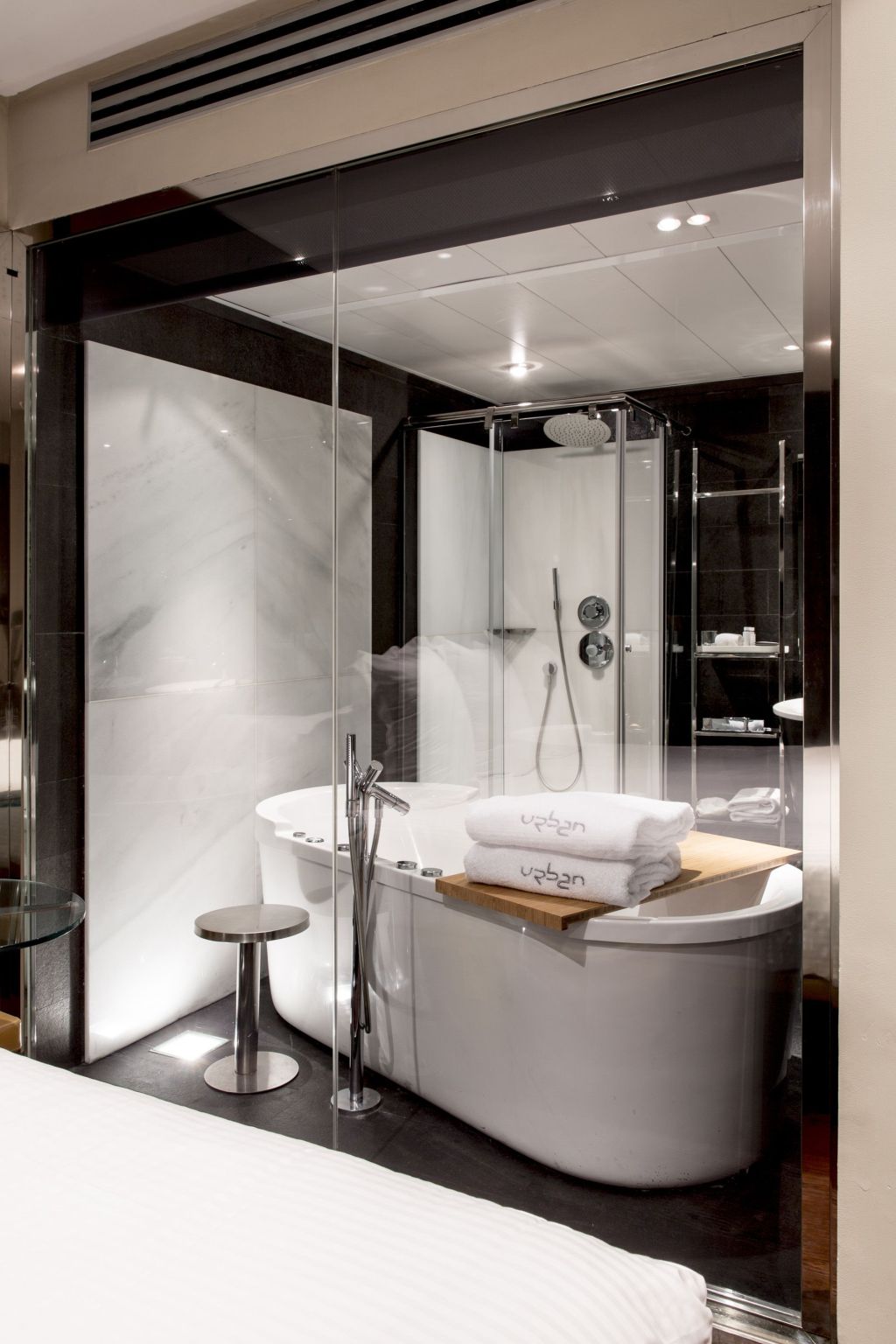 Se ve una bañera empotrada con mampara de vidrio y un lavabo en un cuarto de baño moderno.