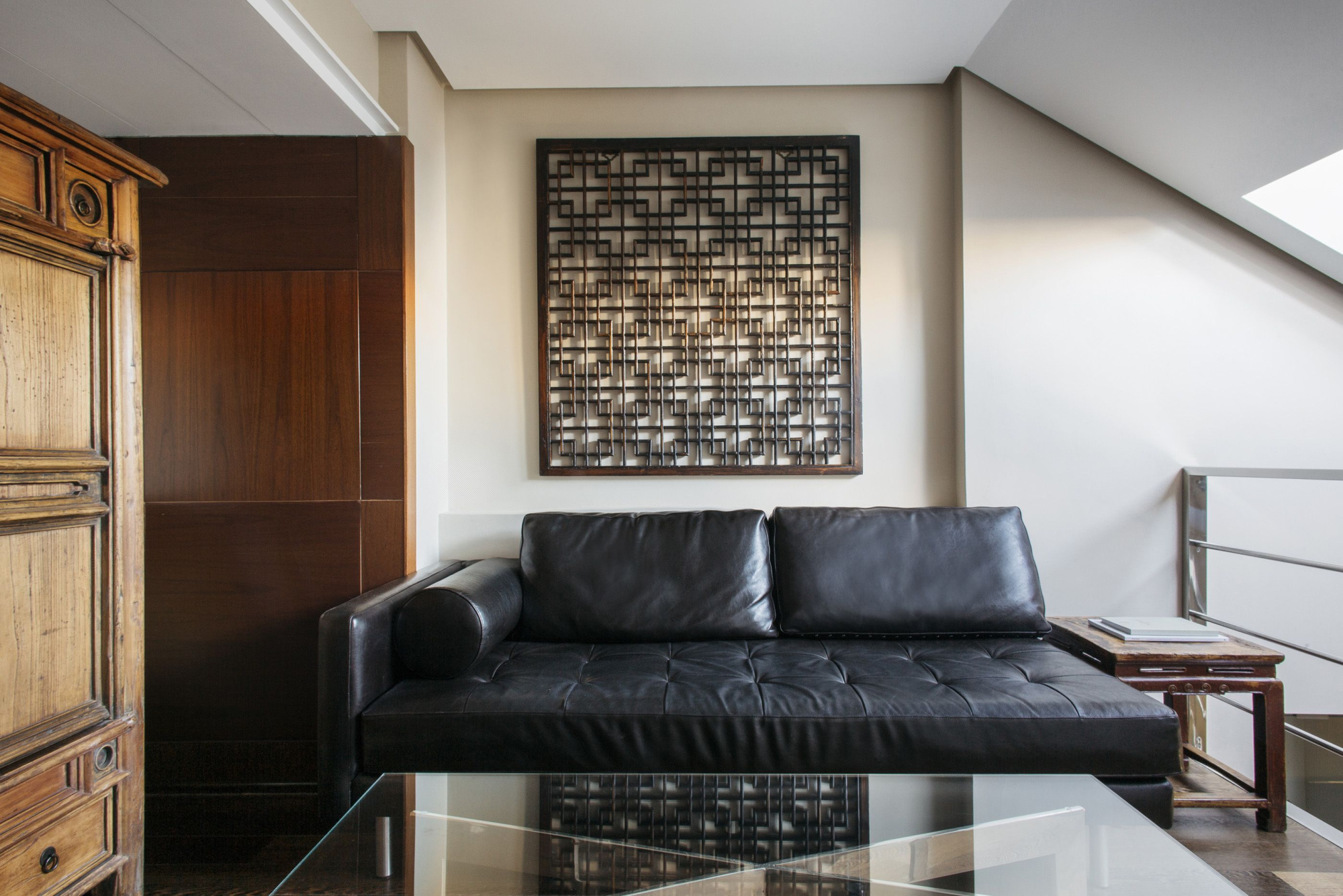 Se ve un sofá de cuero negro, una mesa auxiliar y una pared con un cuadro decorativo.