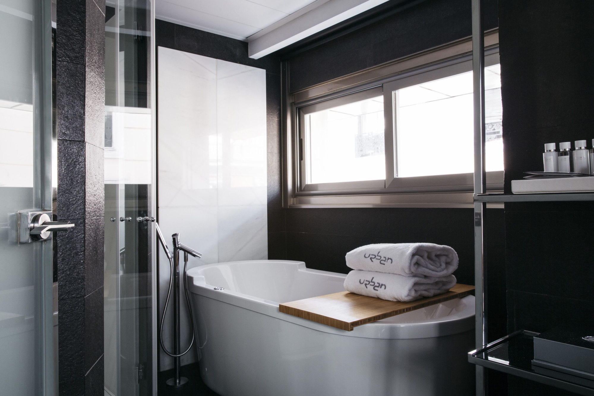 Se ve un baño moderno con bañera, mampara de ducha y lavabo con espejo.
