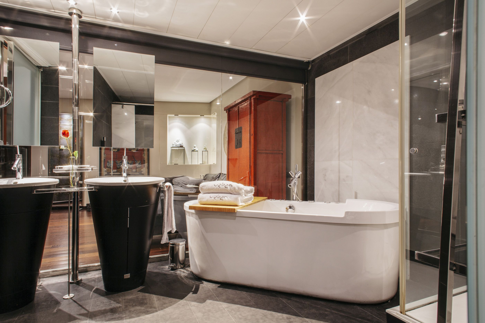 Se ve un baño moderno con bañera blanca, cabina de ducha y lavabo con grifería cromada.