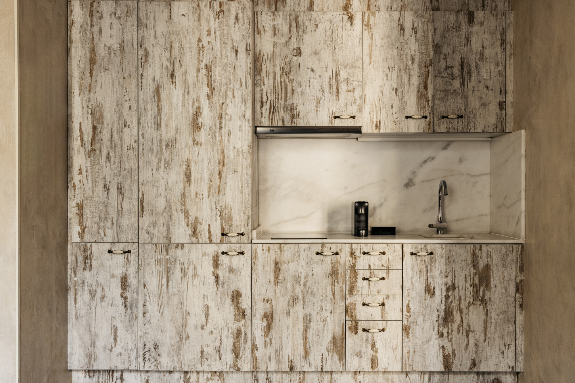 Se ve un mueble de baño con lavabo integrado y grifo sobre una encimera de piedra clara.