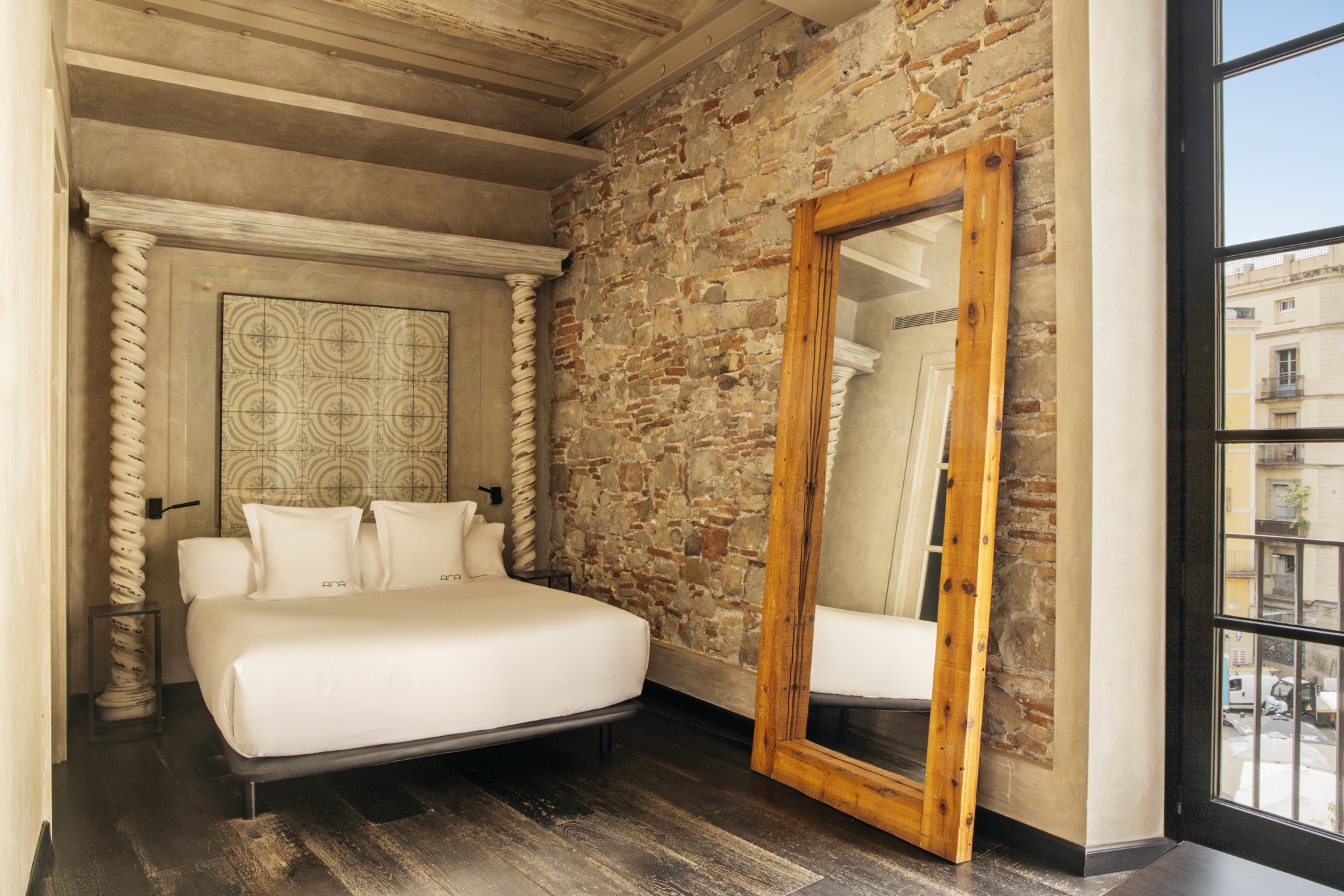 Un dormitorio con cama doble, pared de piedra vista y una puerta de madera abierta hacia otra estancia.