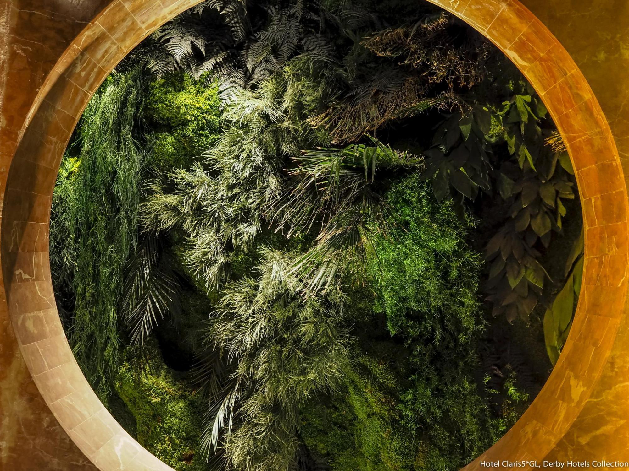 Se ve un jardín vertical verde enmarcado por una estructura circular de color dorado.
