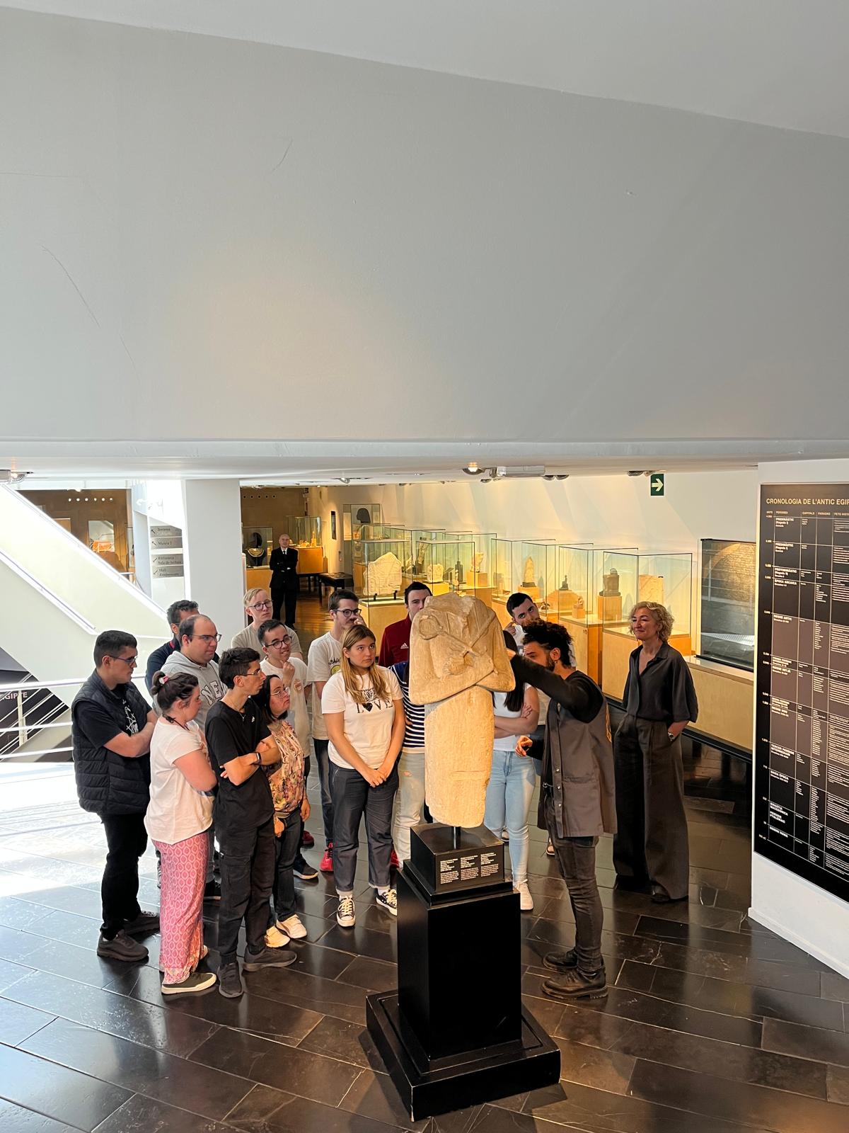 Varias personas observan una exposición en una sala con paneles informativos y vitrinas iluminadas.