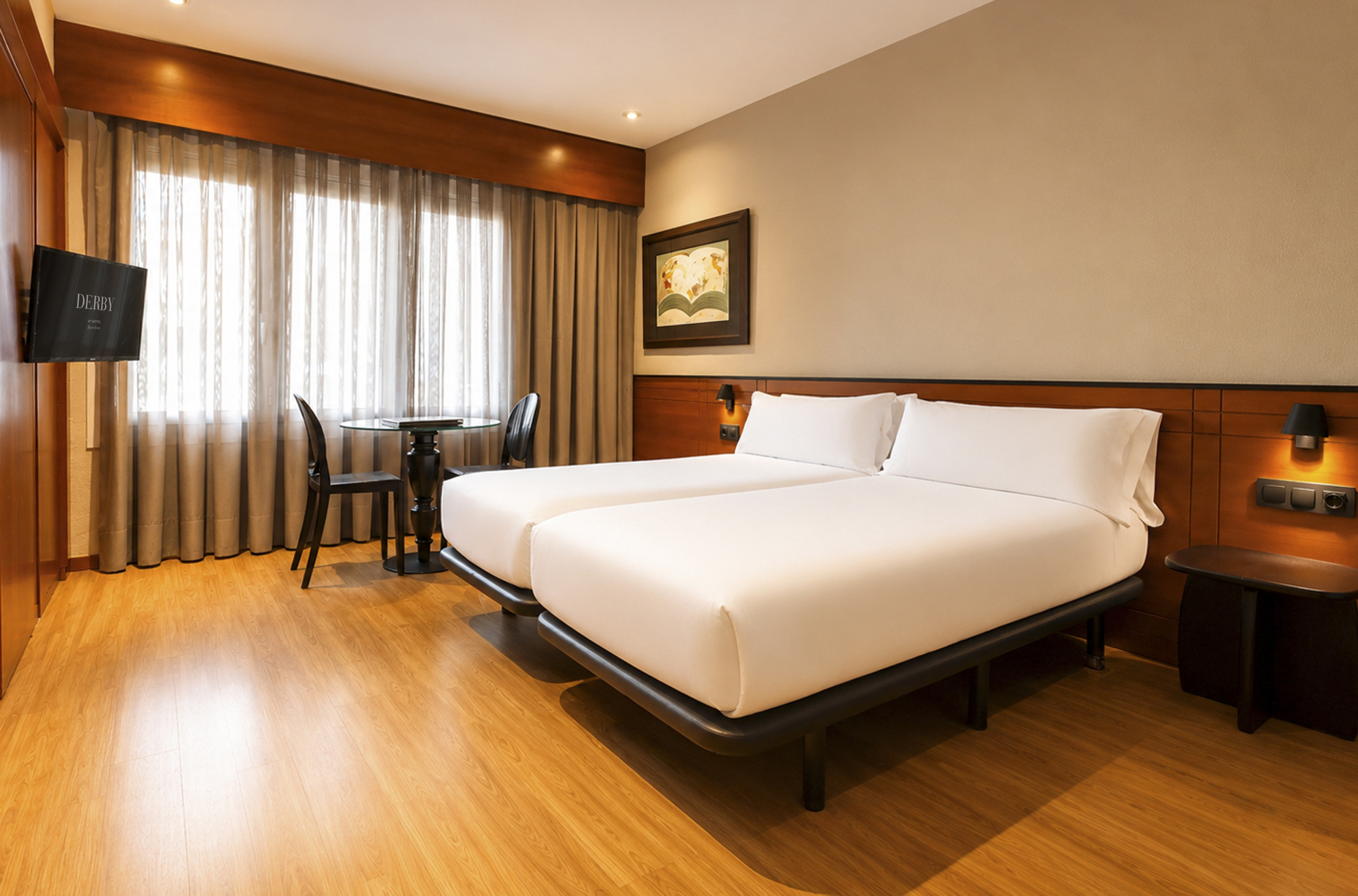 Se ve una cama doble, una mesa de trabajo y una silla junto a una ventana con cortinas en la habitación.