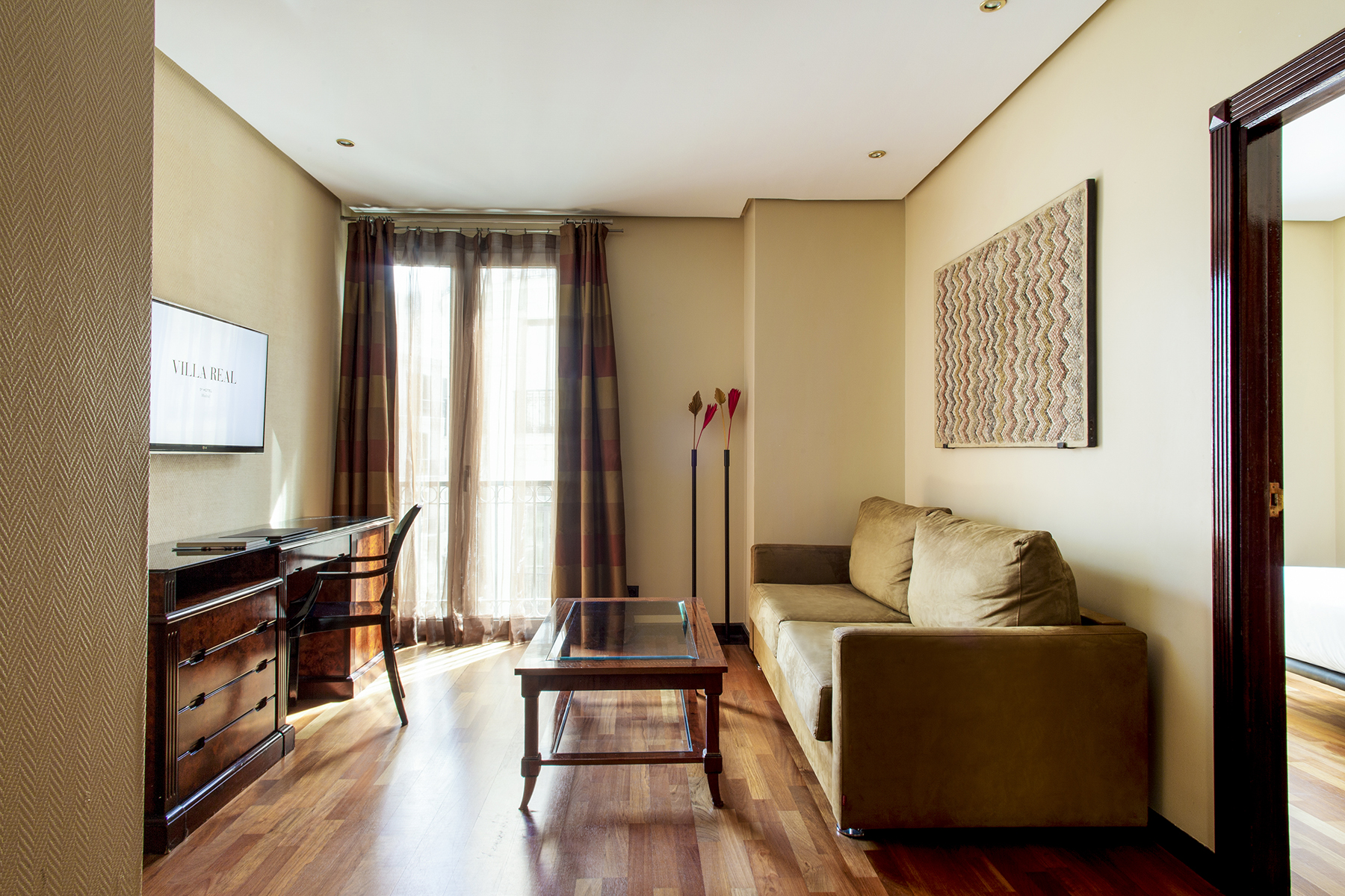 La sala de estar muestra un sofá, una mesa de centro, una cómoda y una puerta con acceso a un balcón acristalado.