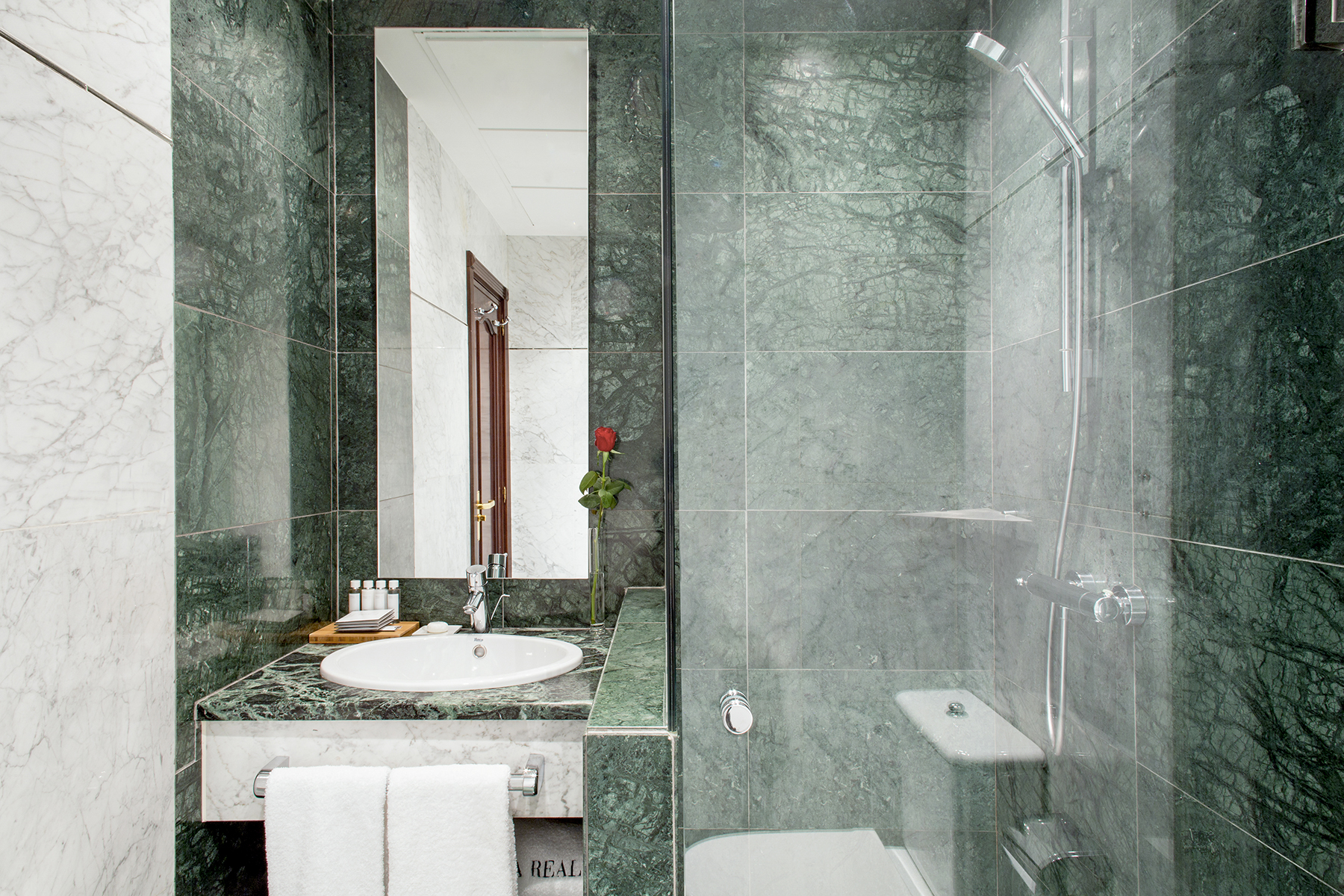 Se ve un baño moderno con lavabo, espejo y cabina de ducha de vidrio.