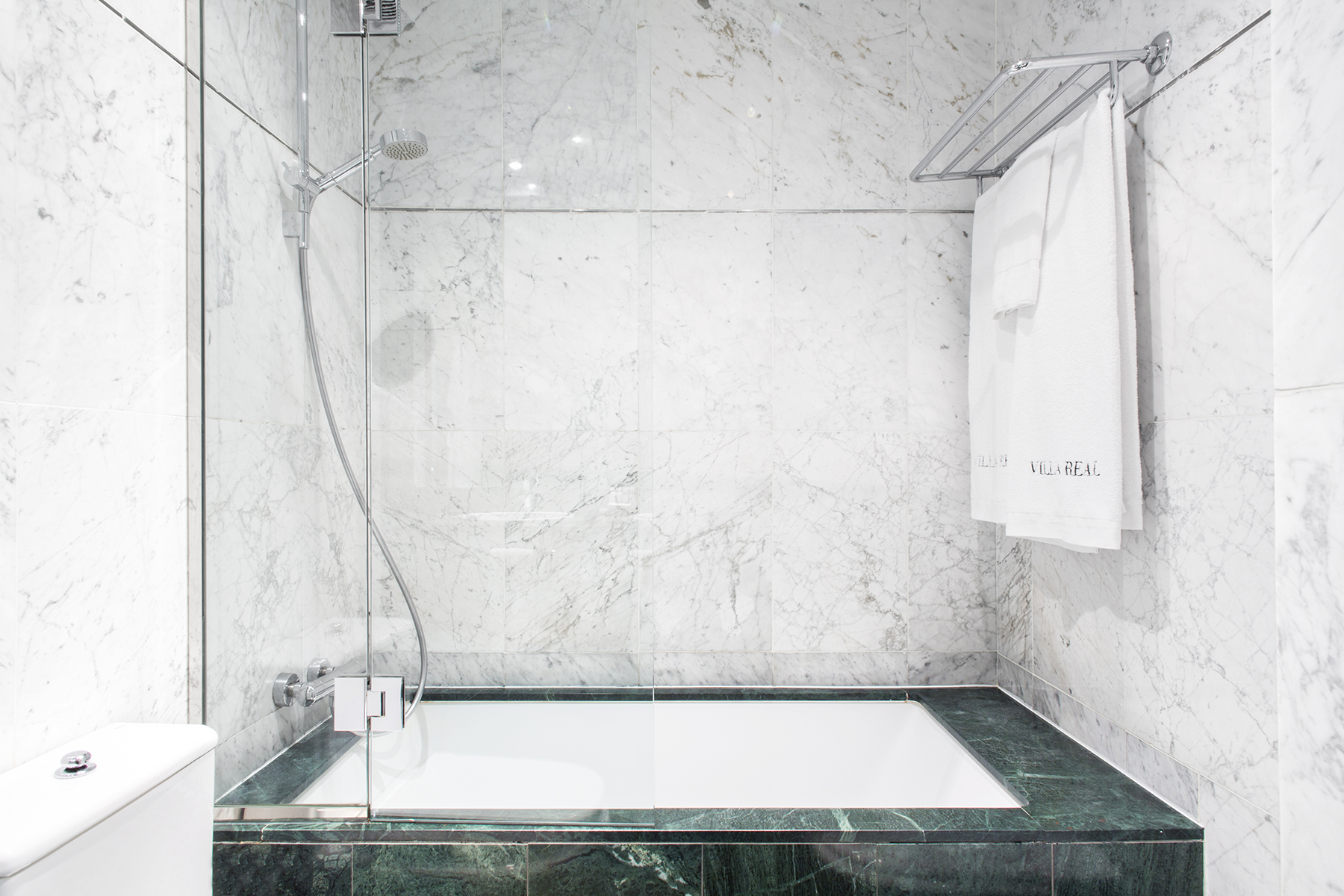 Se ve un baño moderno con bañera rectangular de hidromasaje empotrada y paredes de azulejo claro.