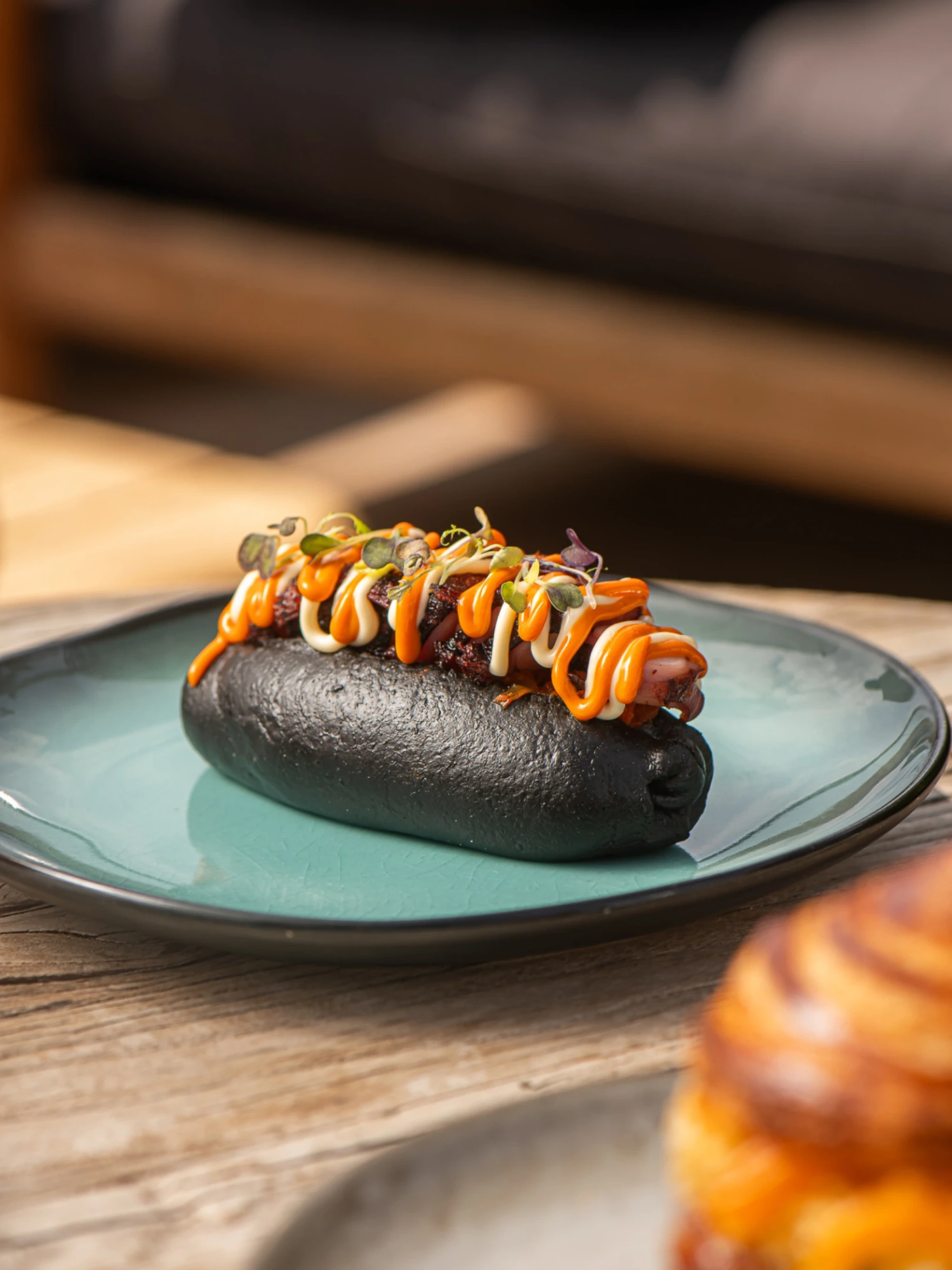 Se ve un plato con un hot dog de pulpo cubierto con salsa sobre un plato verde.