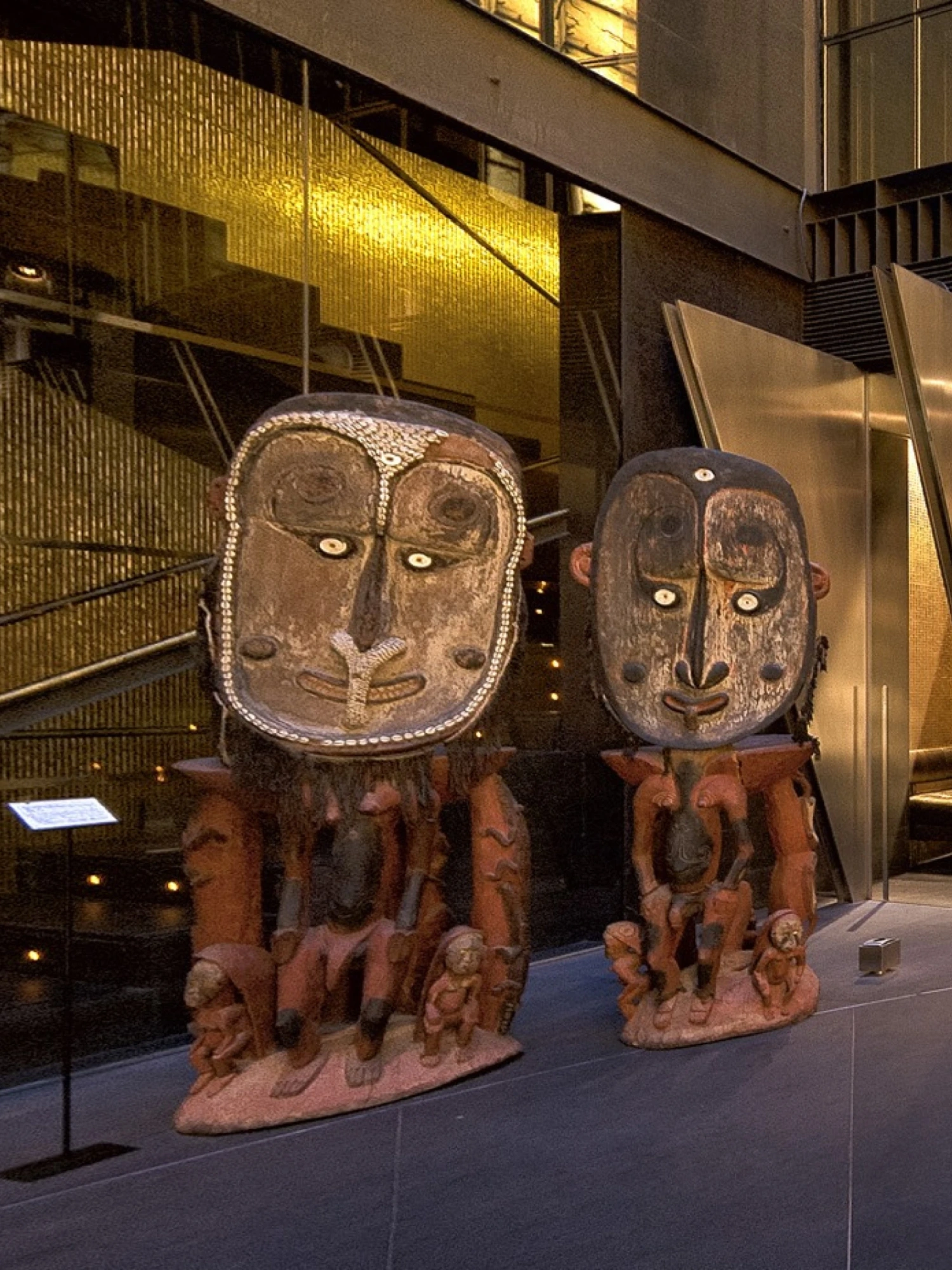 Se observan dos esculturas decorativas de estilo artístico sobre una base en un espacio interior con paredes de vidrio.