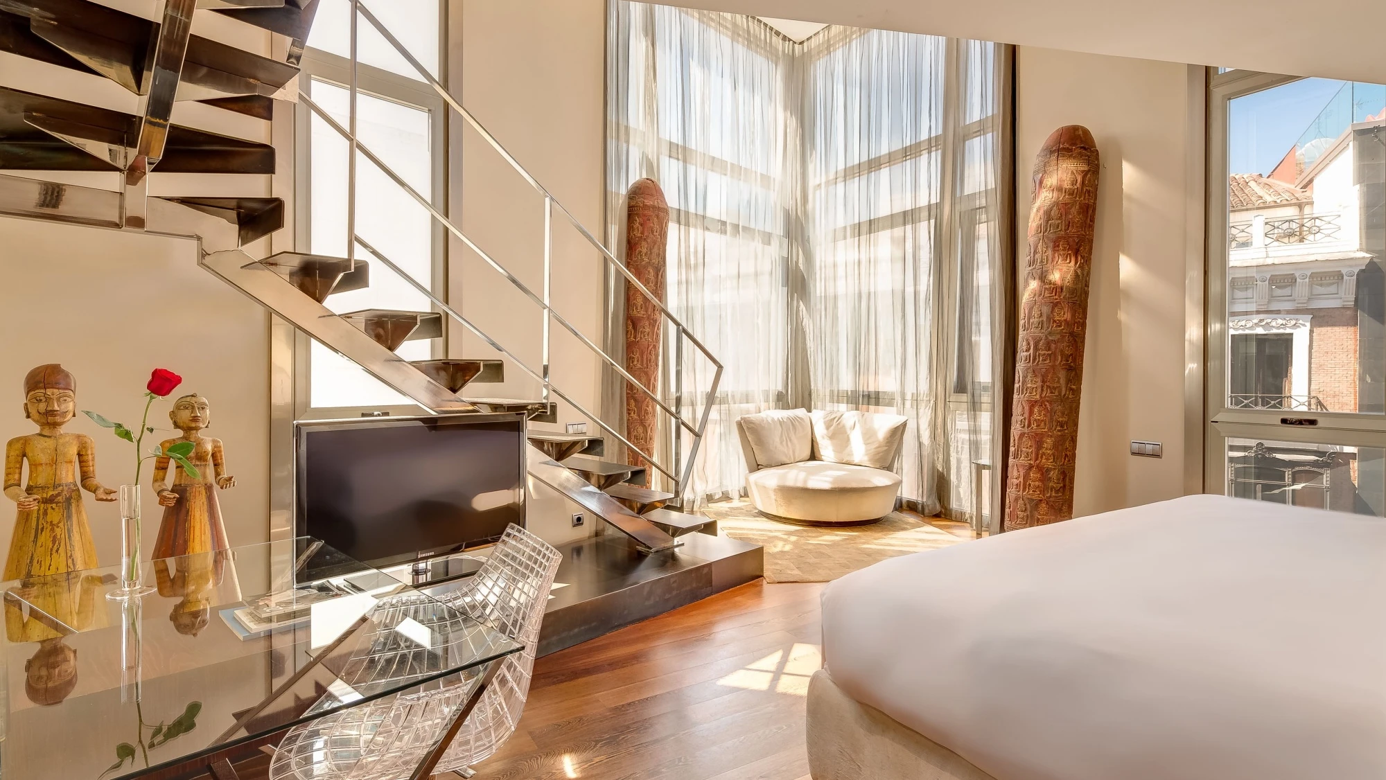 Se ve una cama doble, una zona de estar y una ventana con cortinas en un loft interior.
