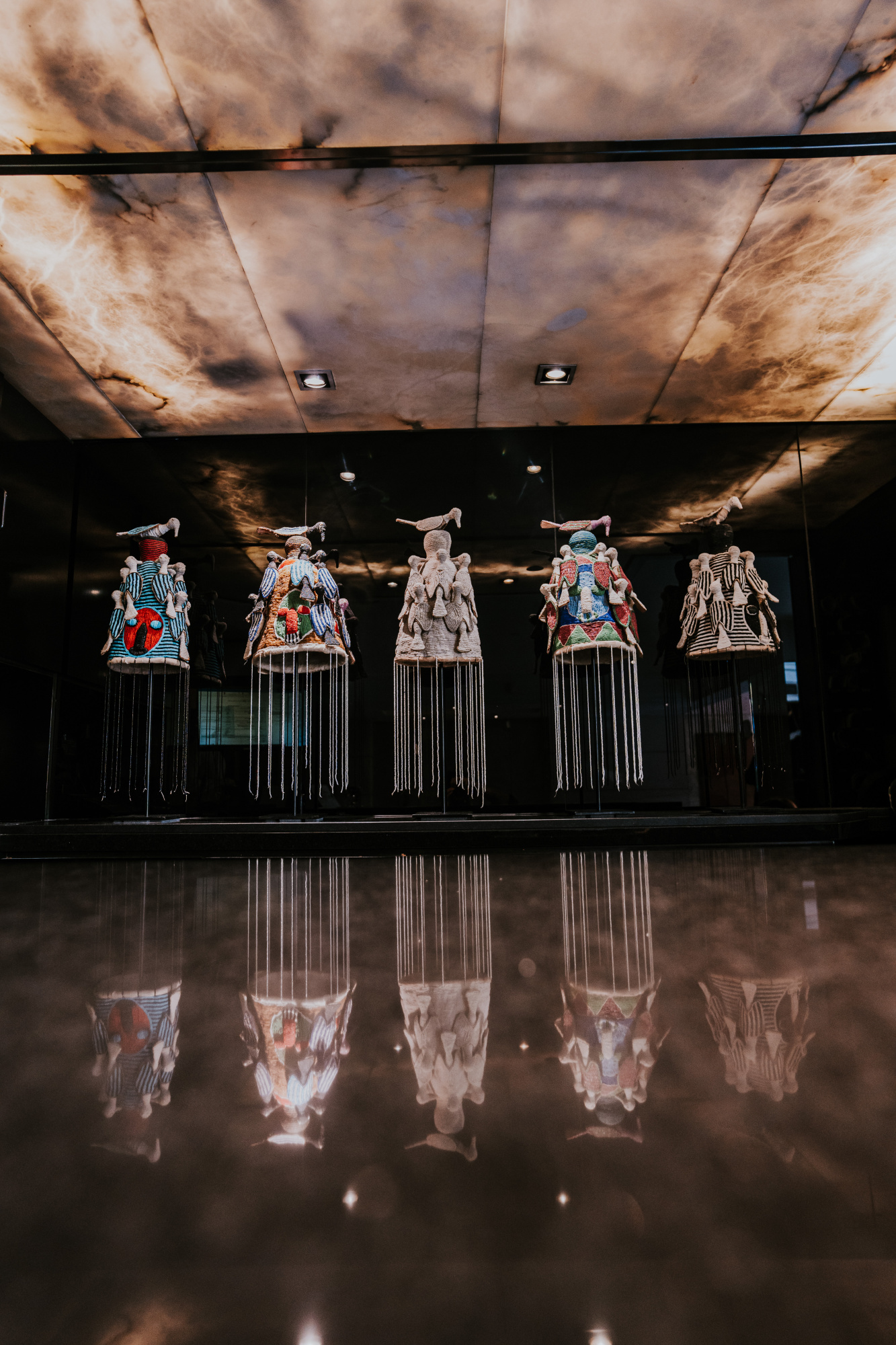 Se ve un escenario con varias figuras de vestuario colgadas y reflejadas en el suelo pulido.