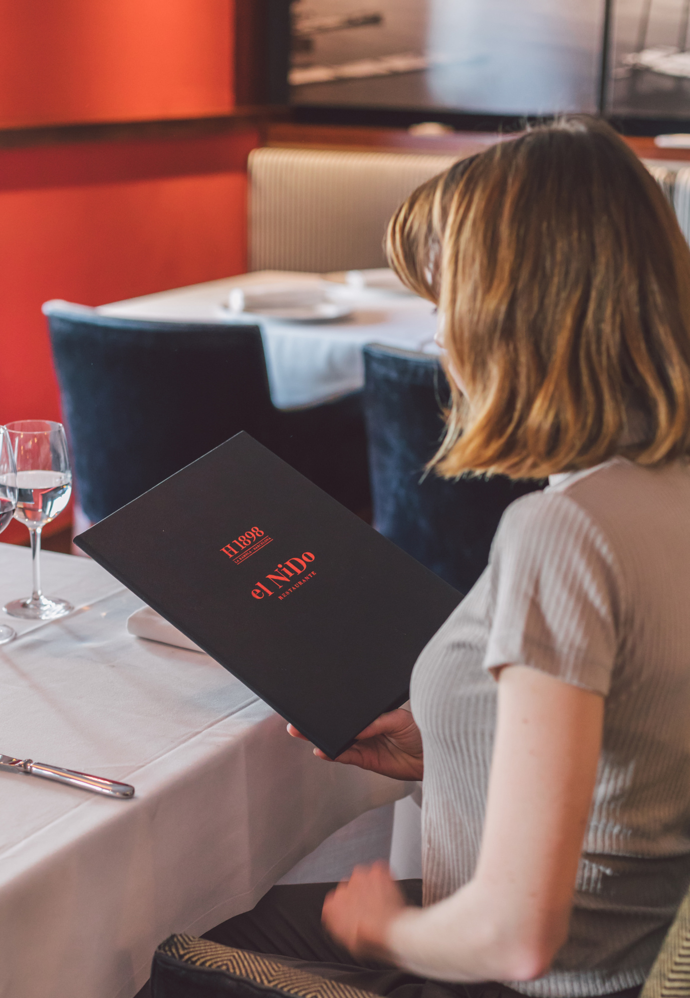 Une personne est assise à une table avec une nappe et une carte noire dans un restaurant.