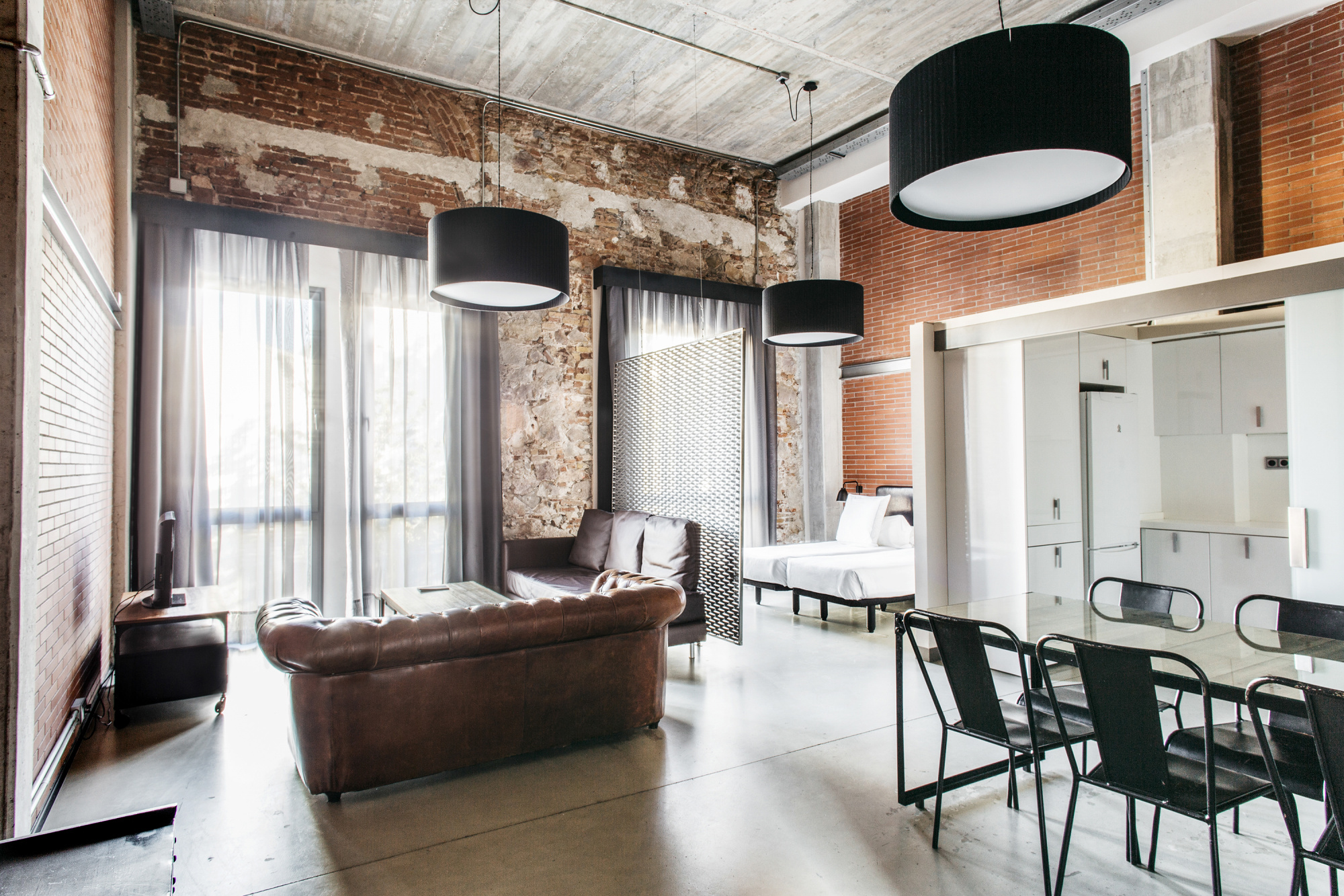 Se ve una sala de estar con sofá de cuero, mesa y sillas, y una zona de cocina al fondo.