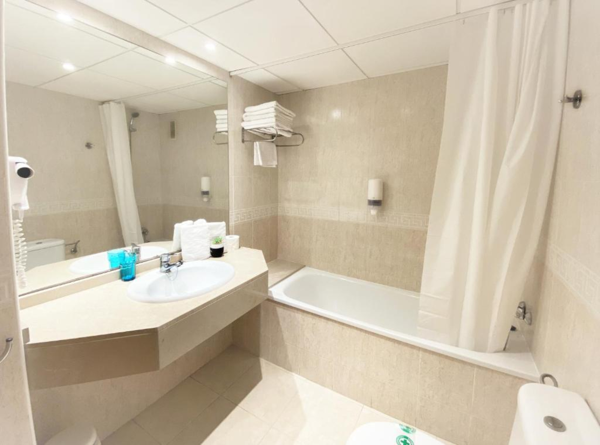Baño moderno con bañera y lavabo en el Aparthotel SunClub Salou, con un diseño funcional y limpio, ideal para relajarse durante la estancia.