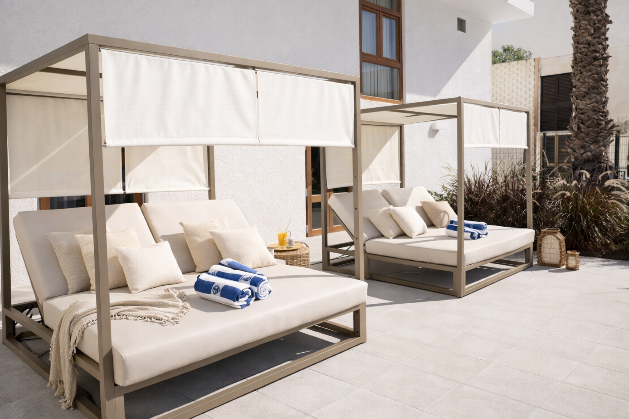 Una cama balinesa de madera oscura con un diseño tradicional, decorada con cortinas blancas que aportan un toque de elegancia y tranquilidad, perfecta para un ambiente relajante en un hotel.