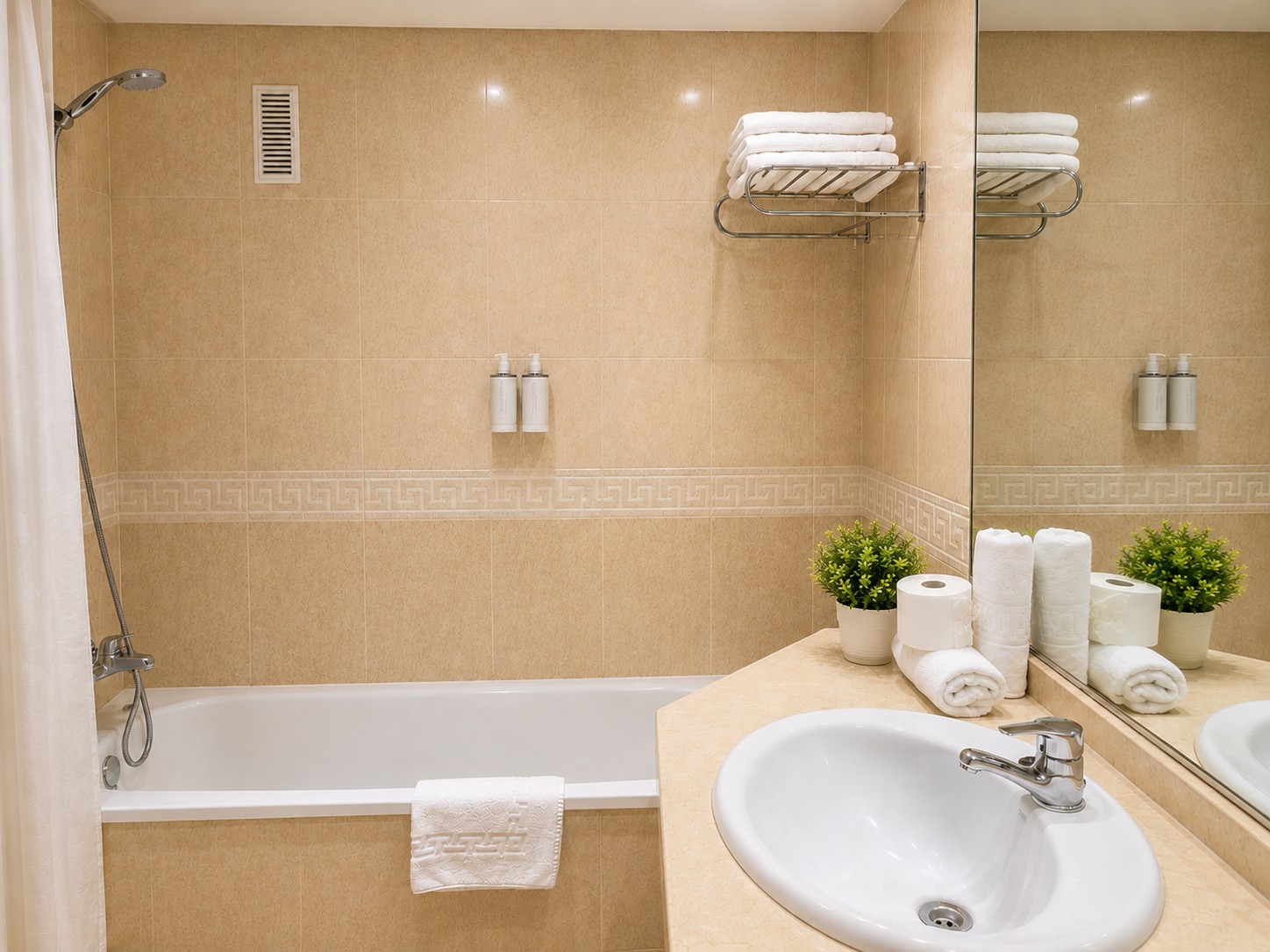 Se ve un baño con lavabo, ducha y toallas dobladas sobre repisas.