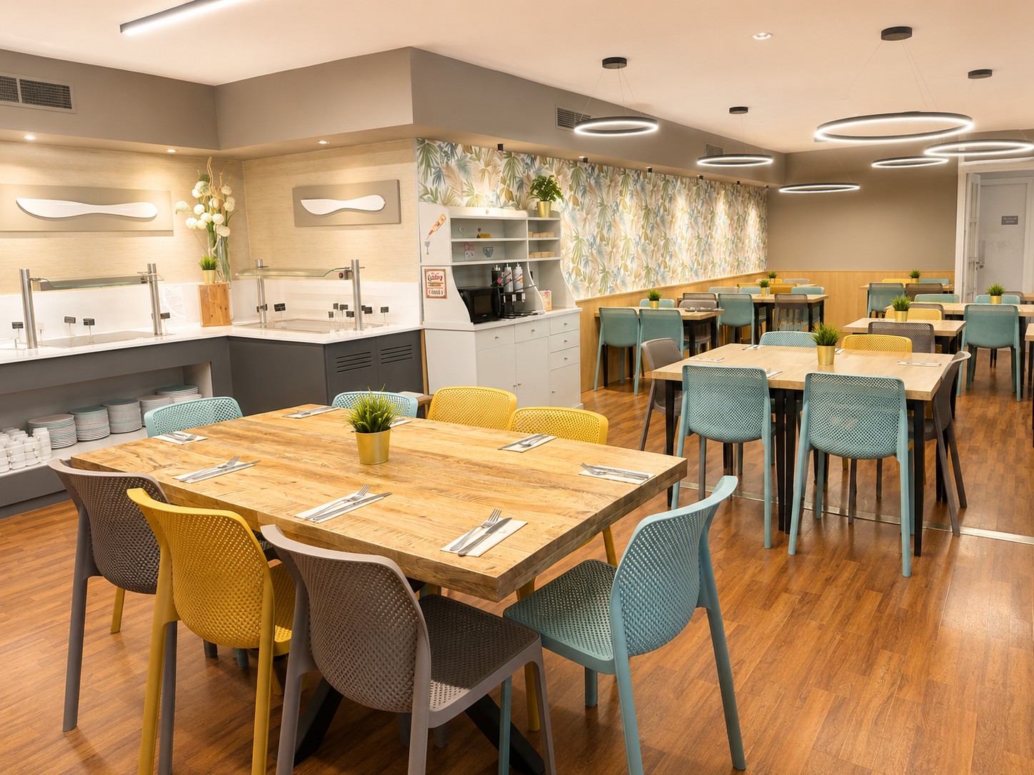 Se ve un comedor tipo buffet con mesas de madera, sillas tapizadas y un área de autoservicio al fondo.