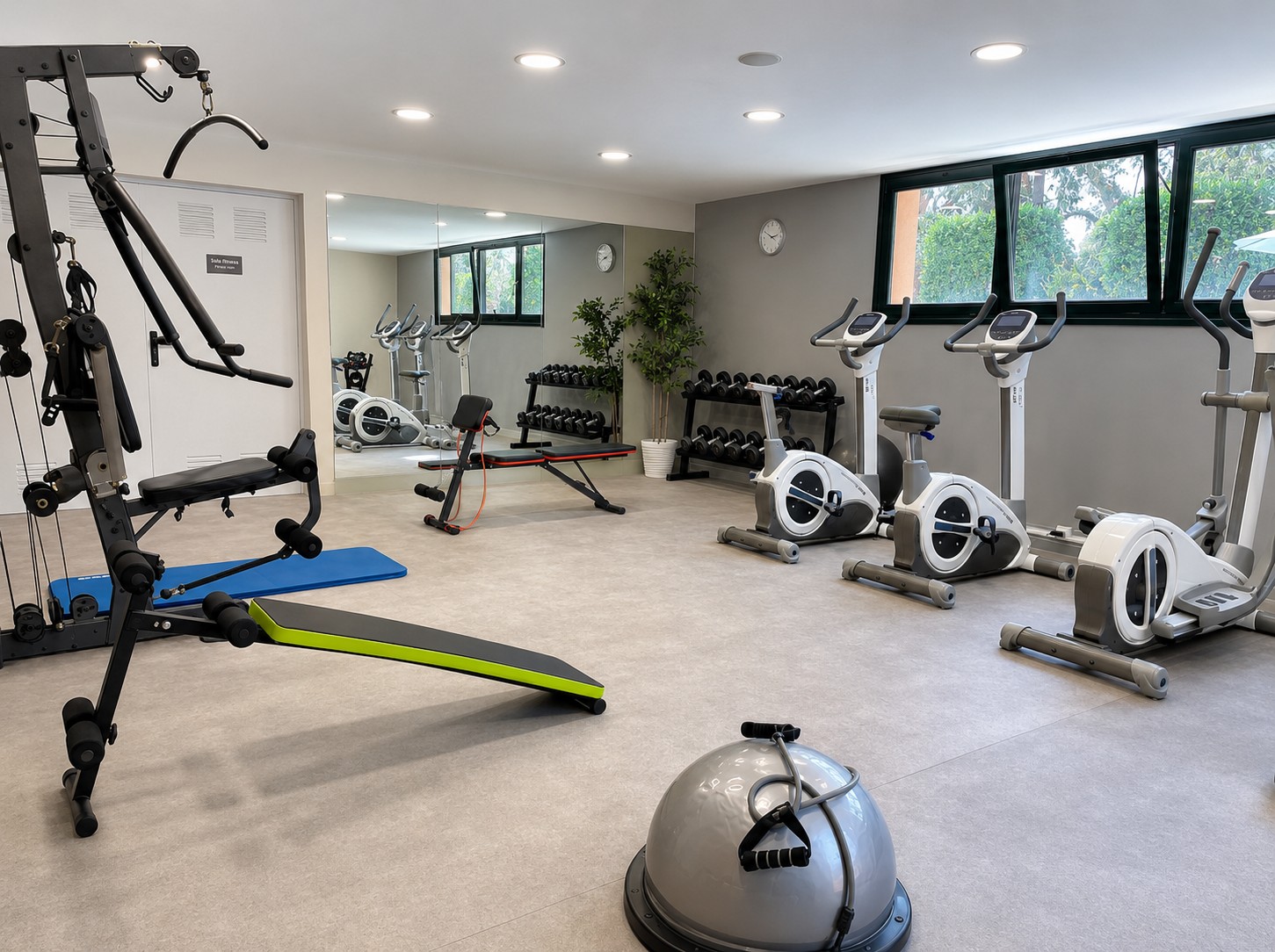Se ve un gimnasio amplio con máquinas de ejercicio y pesas en el suelo.