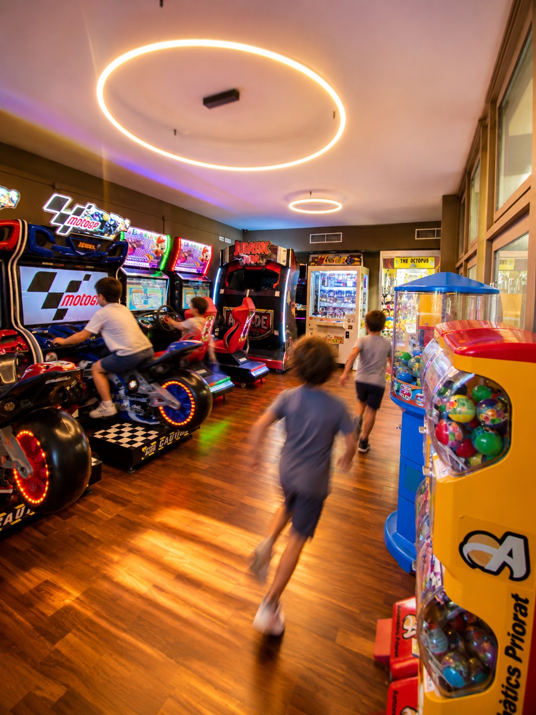 Se ve una sala con máquinas recreativas, juguetes y niños caminando entre los puestos.