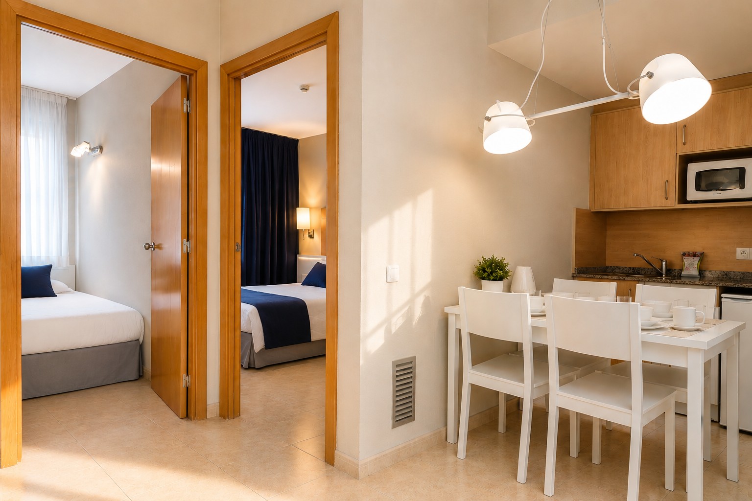 Se ve una zona de estar con mesa de comedor, sillas y una cocina integrada junto a una sala con cama.
