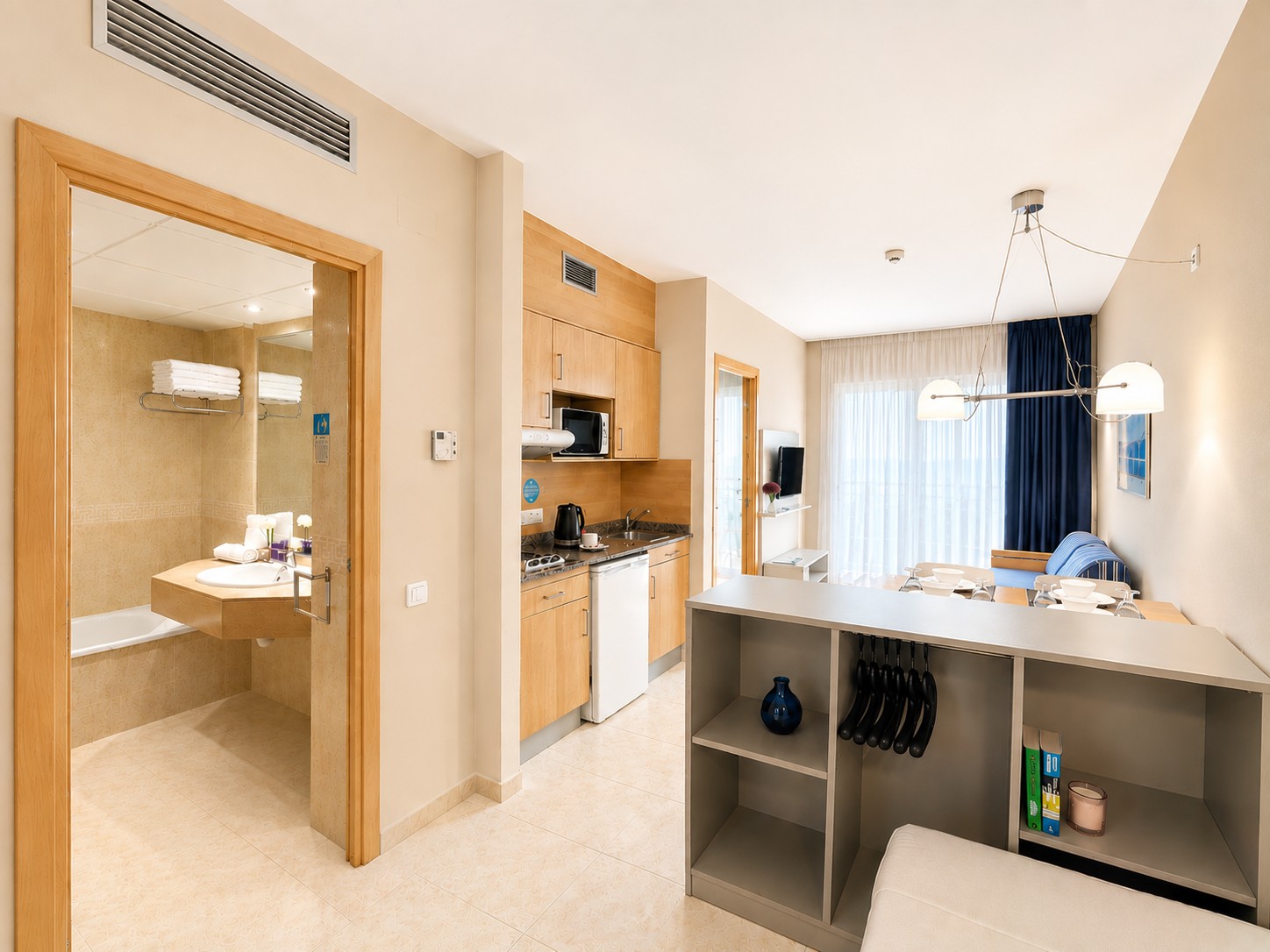 Se ve una zona de estar con cama, una cocina integrada y un baño con ducha al fondo.
