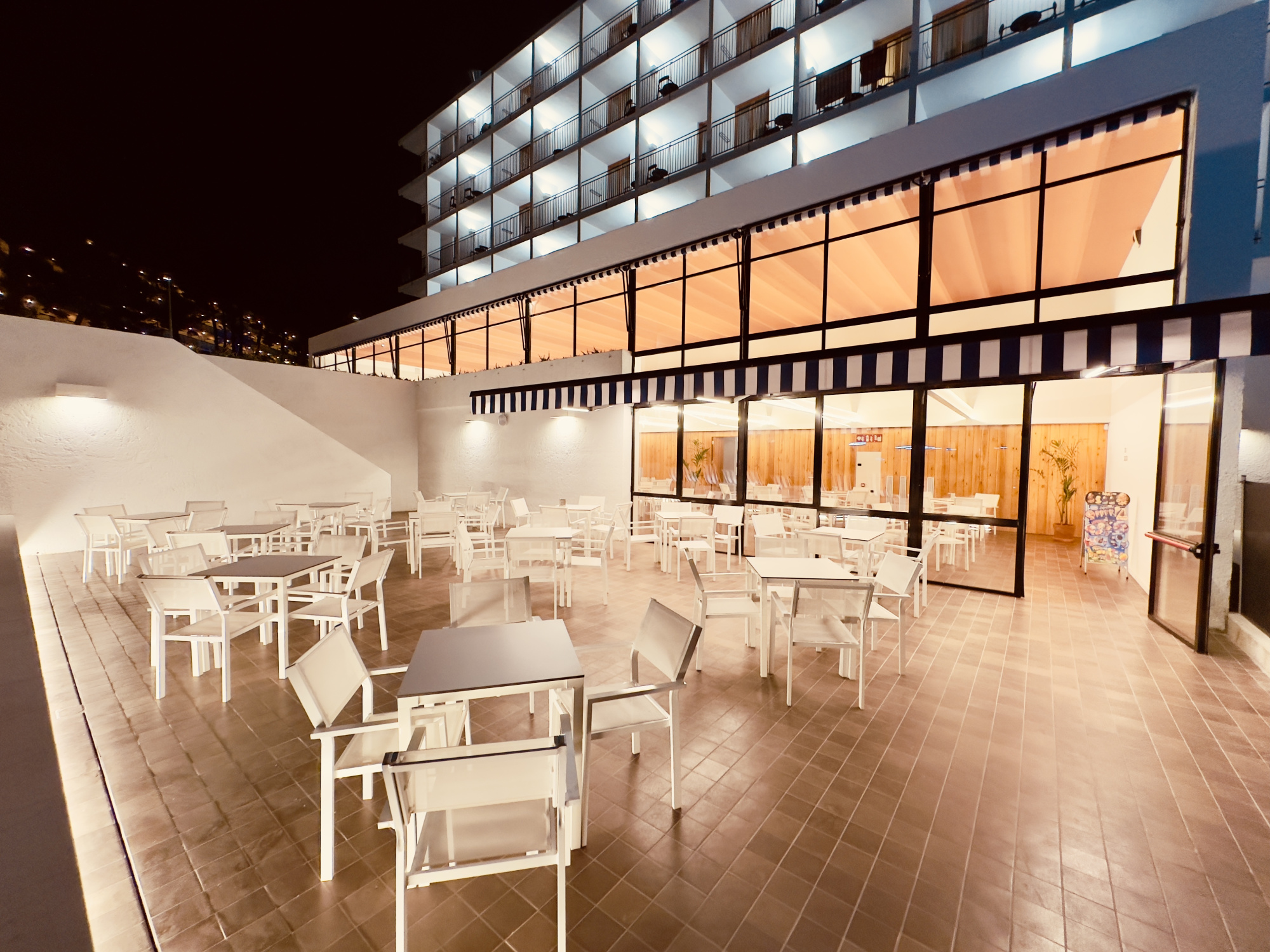Una terraza al aire libre con mobiliario de madera y sombrillas, ideal para relajarse y disfrutar del entorno. El ambiente transmite una sensación de confort y tranquilidad, perfecta para los huéspedes.