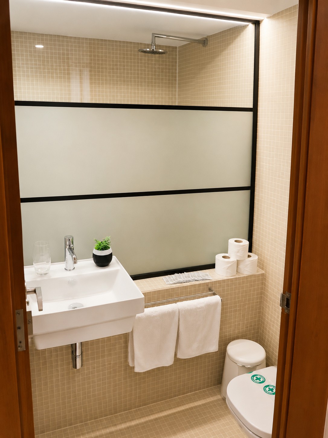 Se ve un baño con lavabo blanco, inodoro y una mampara de ducha con azulejos claros.