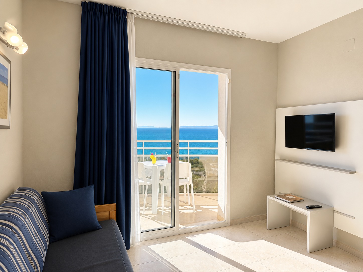 Se ve un sofá junto a una ventana con acceso a una terraza y vistas al mar.
