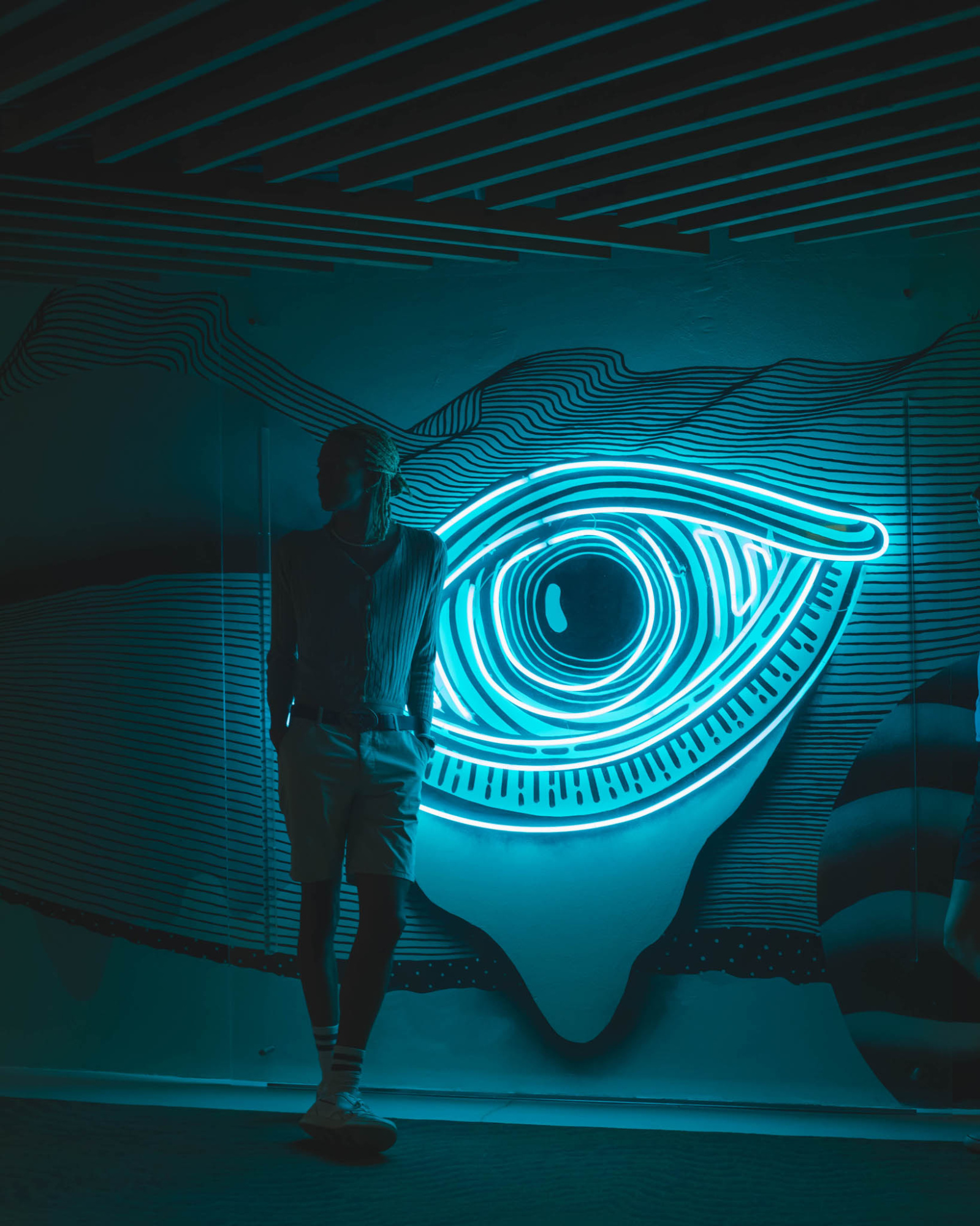 Una persona camina por un pasillo con un gran círculo luminoso en la pared.