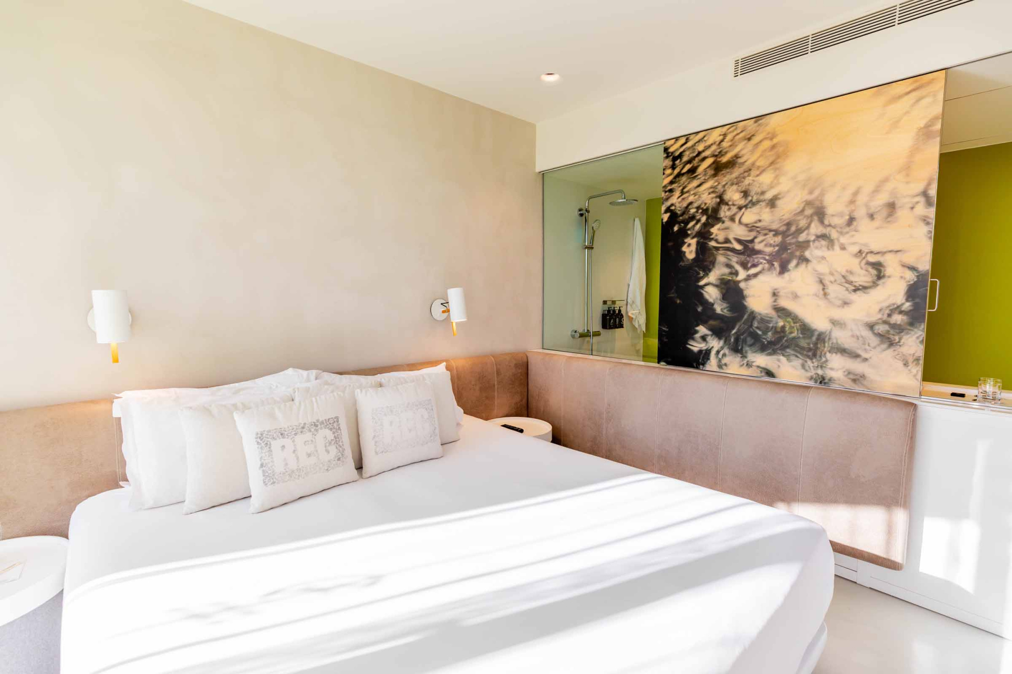 El dormitorio muestra una cama doble con ropa de cama blanca y una pared con un cuadro grande.