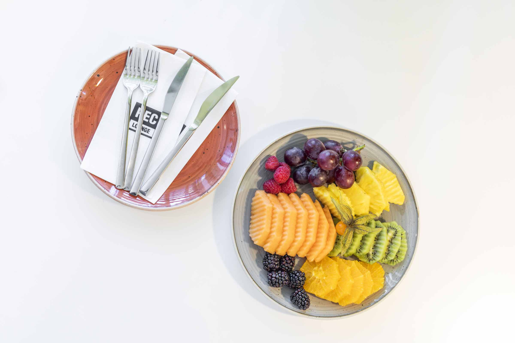 Sirven un plato con frutas y rebanadas de pan junto a una servilleta doblada.