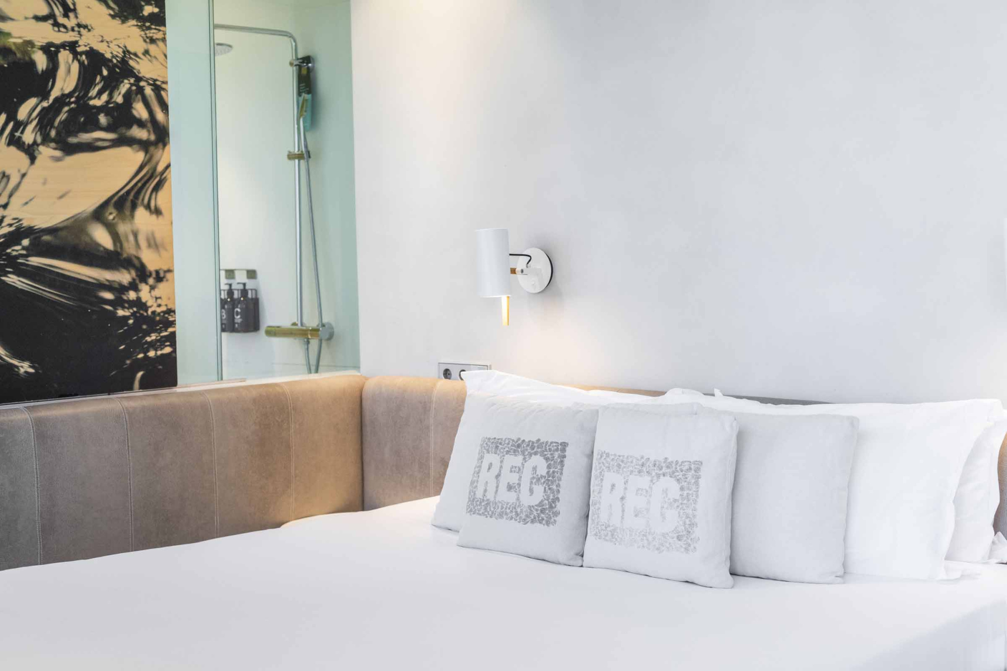 Se ve una cama con almohadas y una cabecera tapizada gris en una habitación.