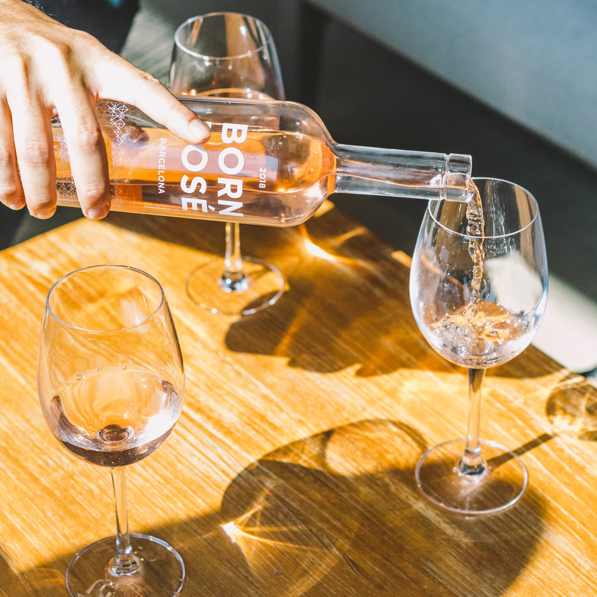 Sirven una botella de vino y tres copas sobre una mesa de madera.