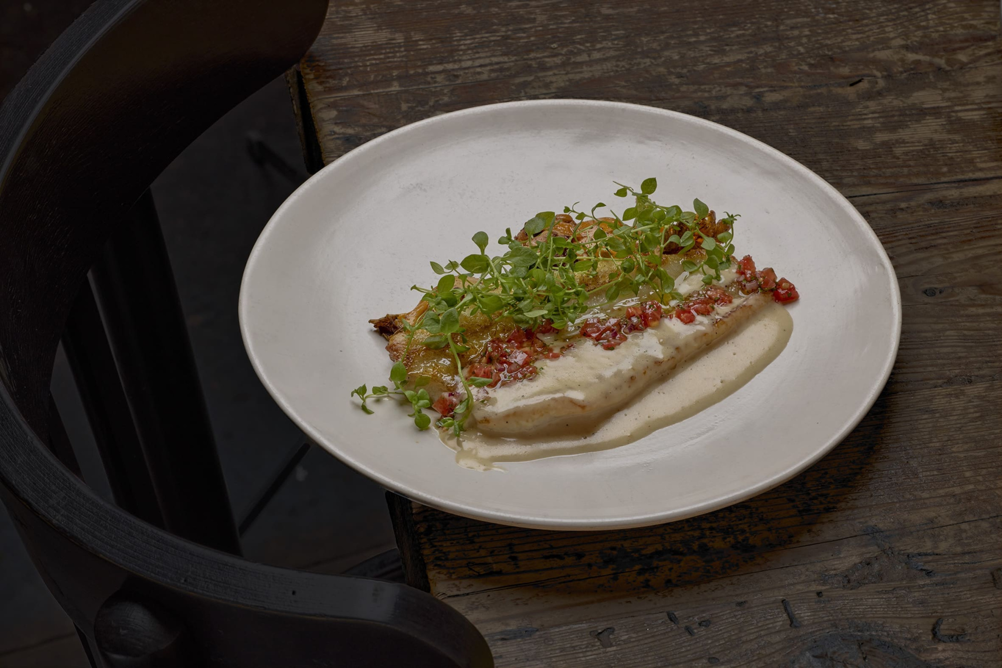 Se sirve un plato con una porción de comida en un plato blanco sobre una mesa de madera.