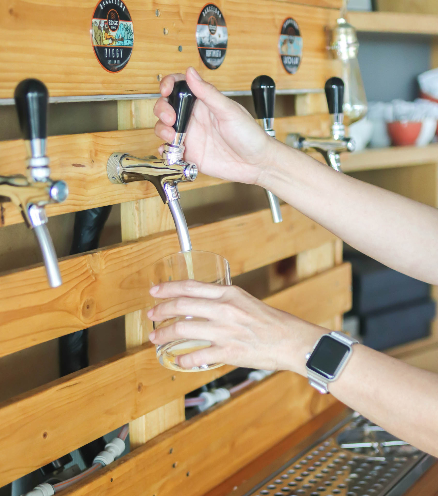 Una persona sirve bebidas desde un grifo de cerveza en una barra de madera.