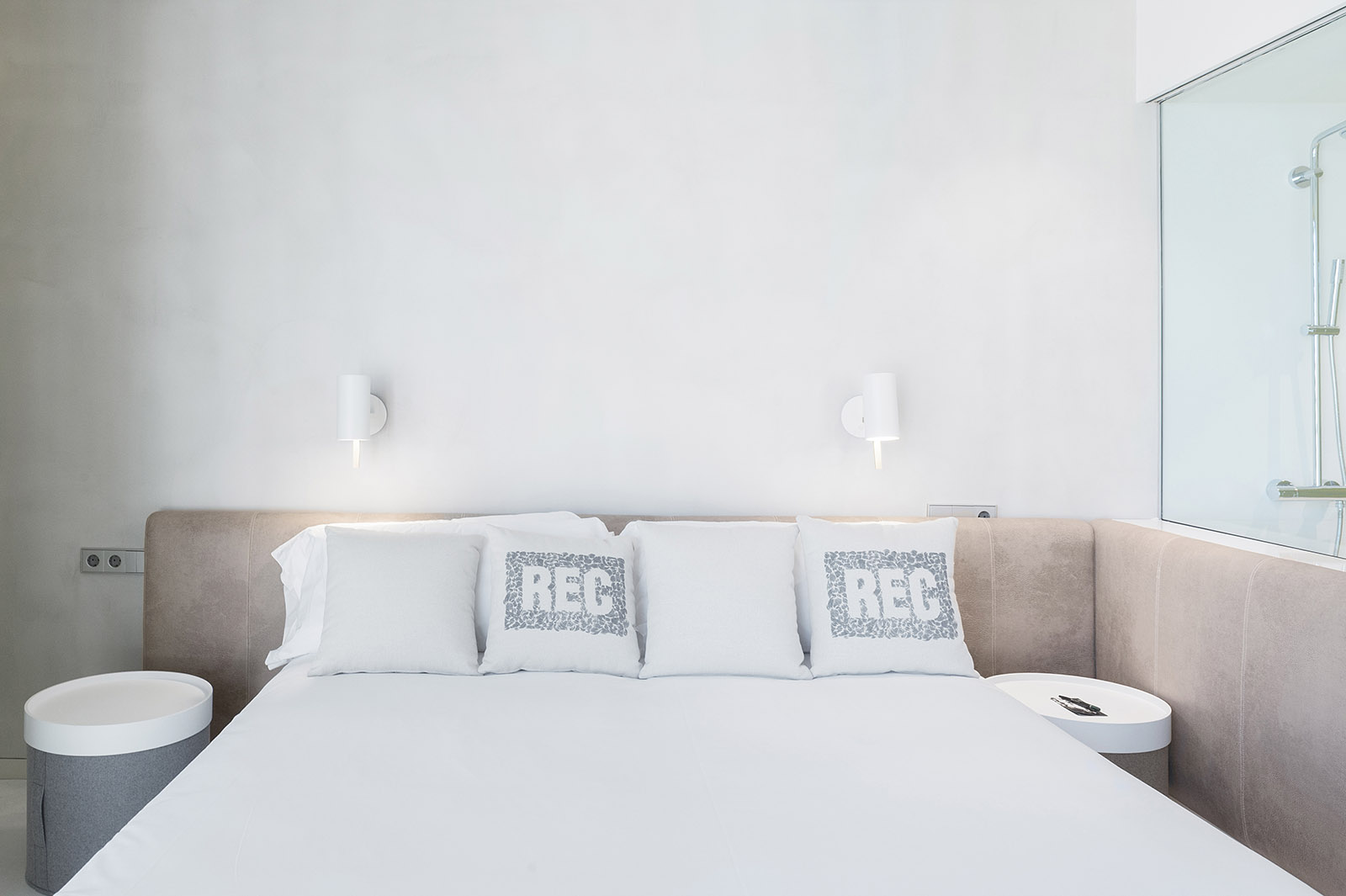 La imagen muestra una cama doble con almohadas y dos mesitas laterales en una suite.