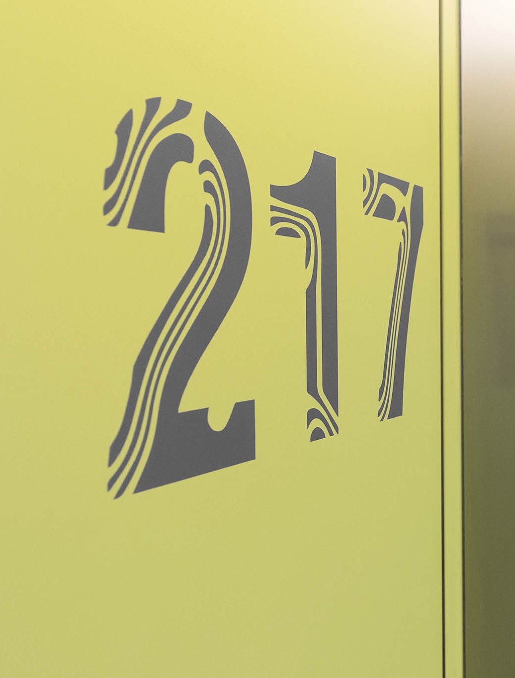 Se ve una puerta amarilla con el número 21 y un pasillo al fondo.