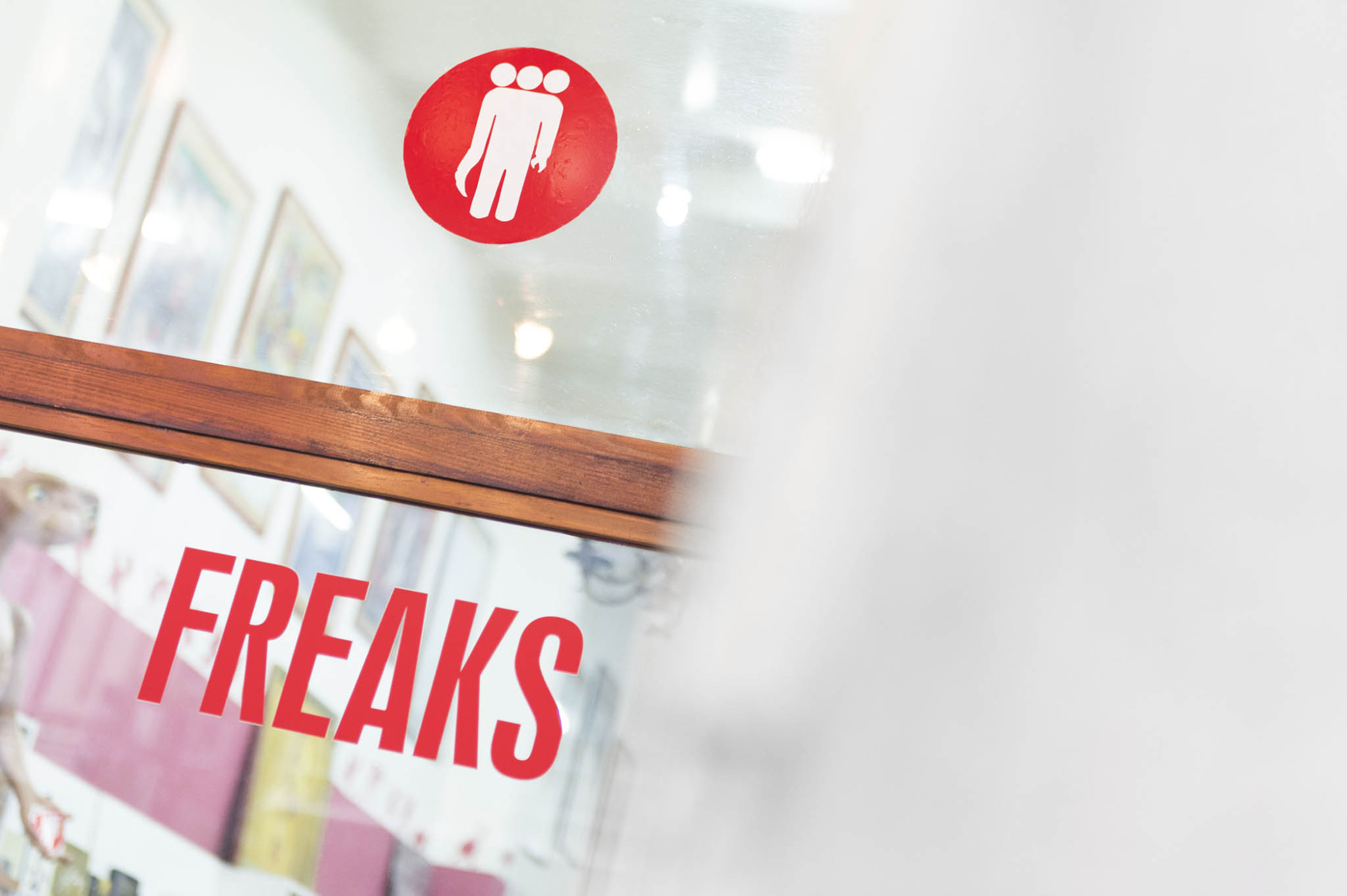 Se ve un letrero rojo con el texto “FREAKS” y un icono blanco sobre una pared interior.