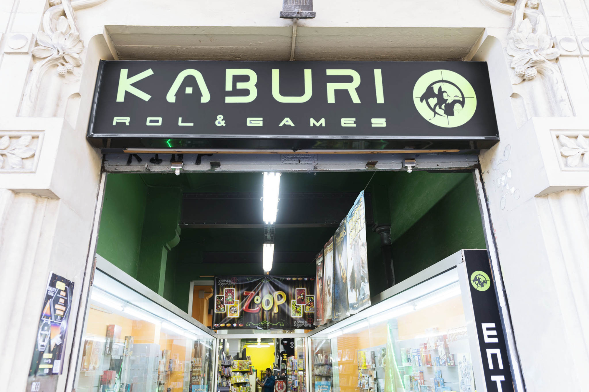Se ve la entrada de un local con el letrero Kaburi & Games y el interior iluminado.