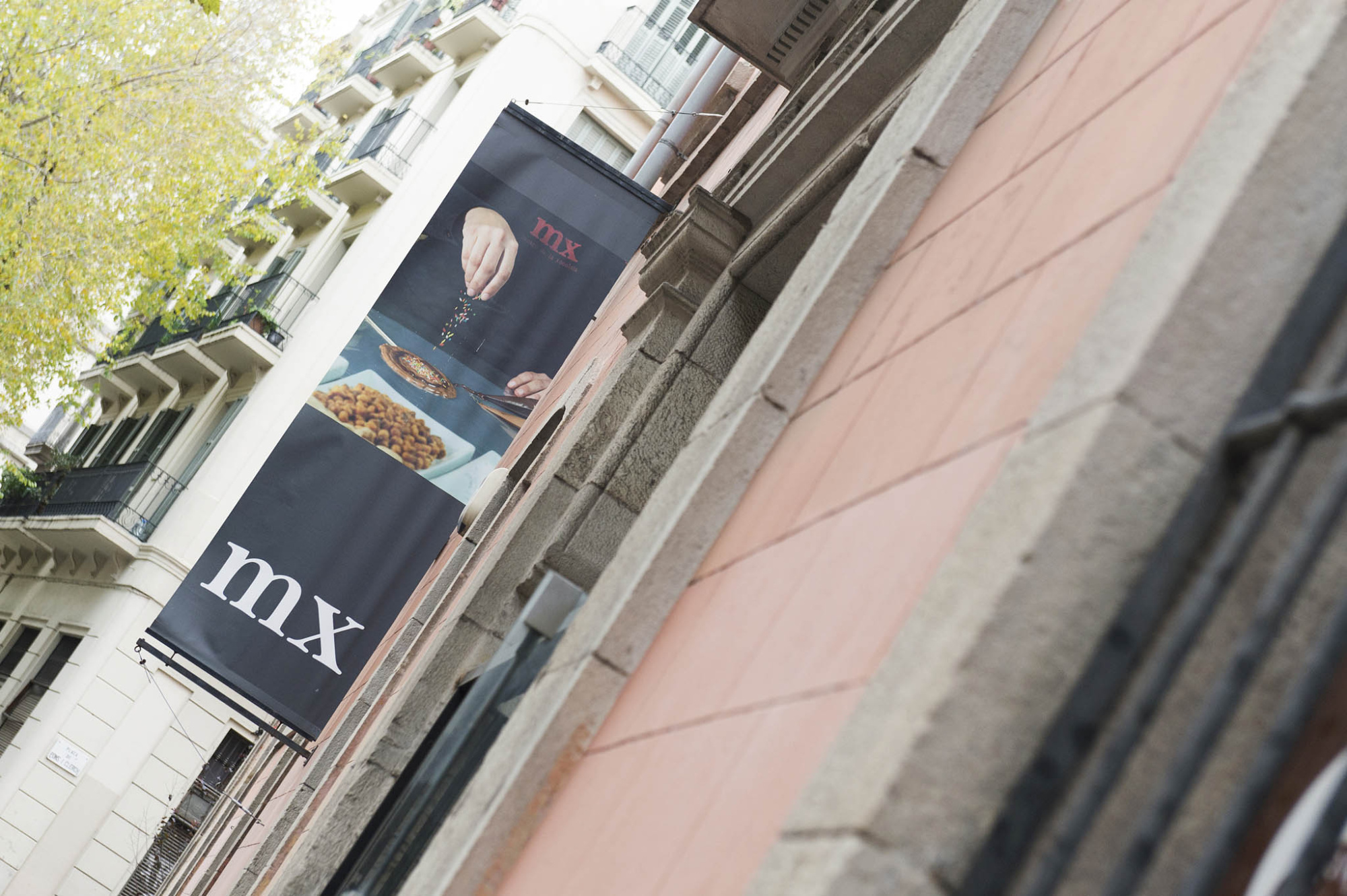 Se ve una fachada de edificio con un toldo y carteles en la calle.