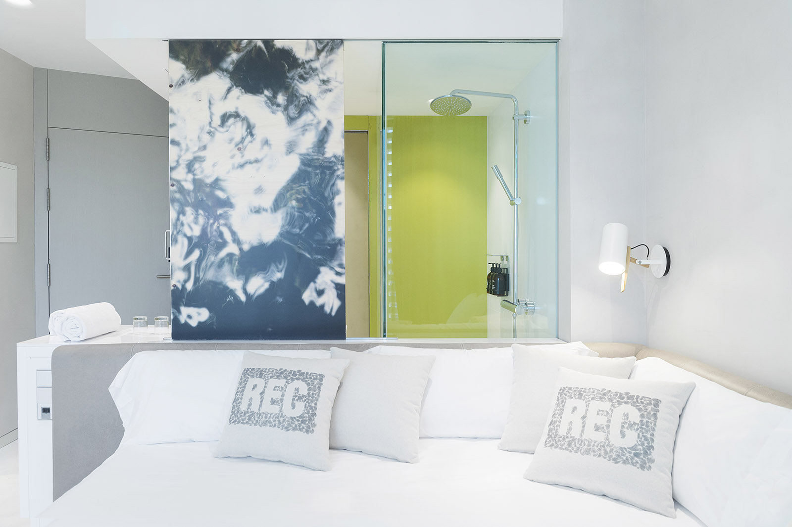 Se ve un sofá blanco con cojines grises y una pared con un panel gráfico detrás.