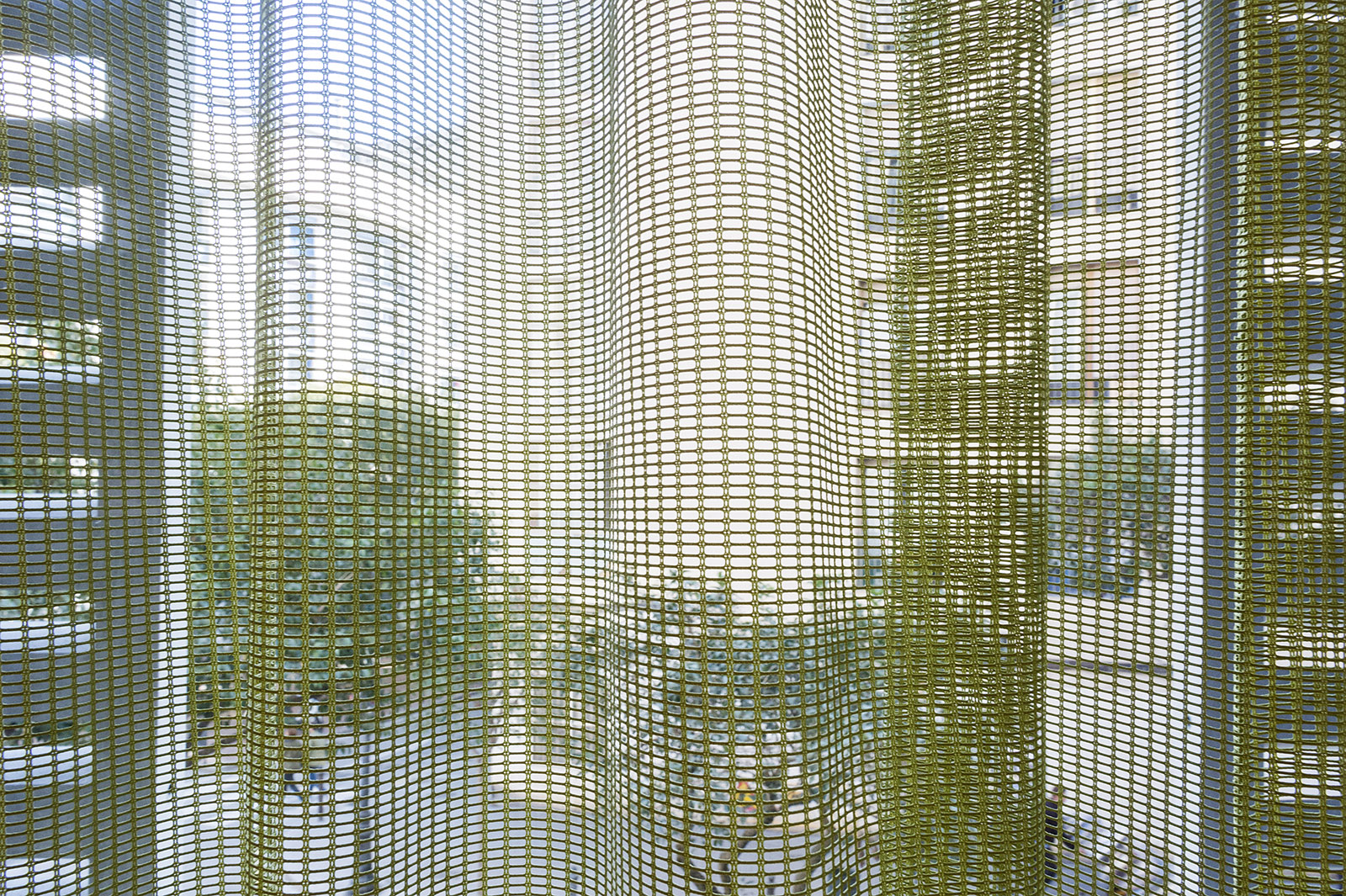 Se ven cortinas de malla translúcida frente a una ventana con luz natural.