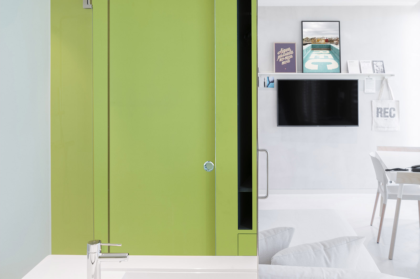 Se ve una puerta verde y una cama con una mesa blanca en una habitación.