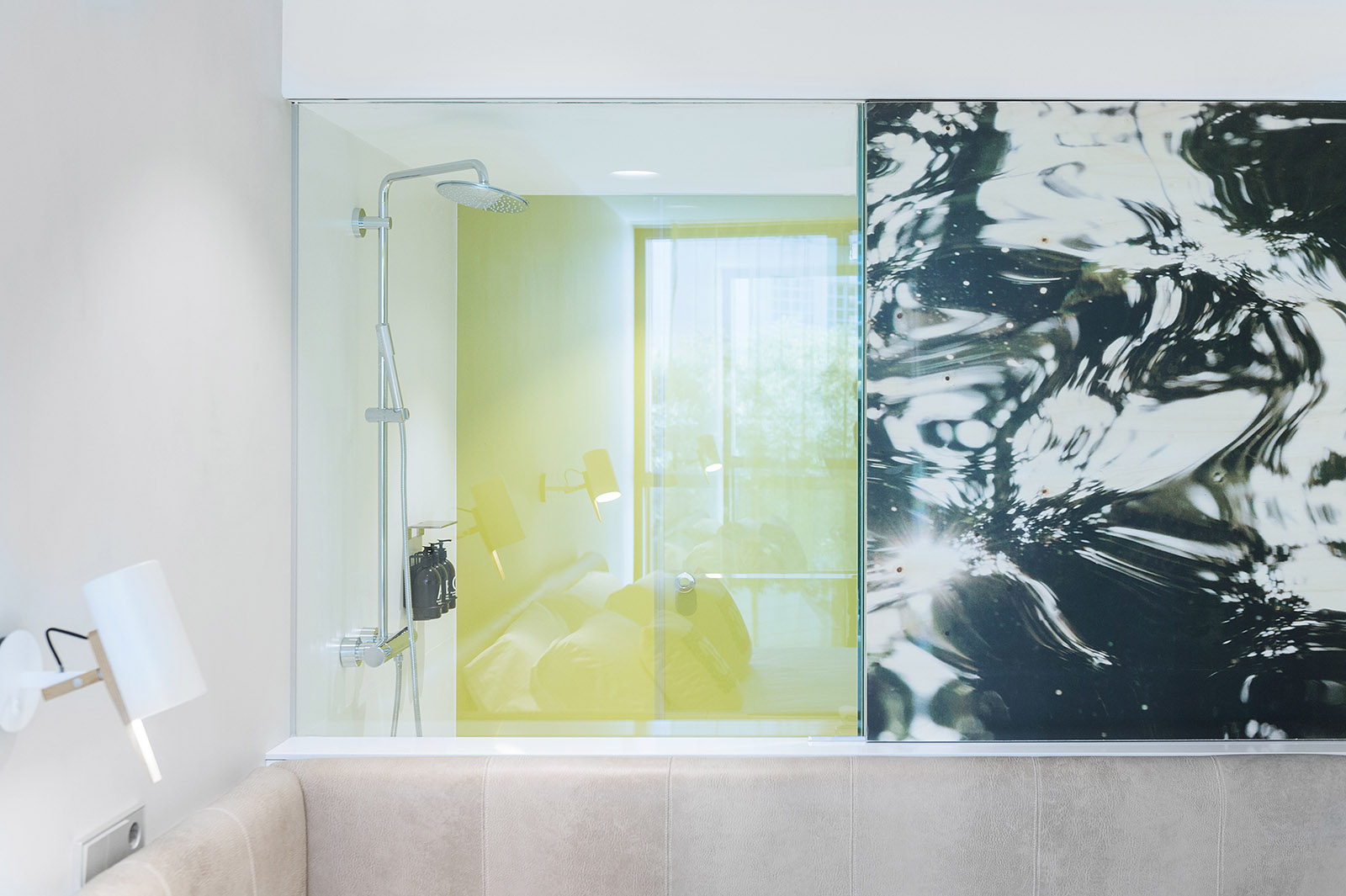 Se ve una zona de baño con mampara de ducha de vidrio y una pared con decoración en blanco y negro.