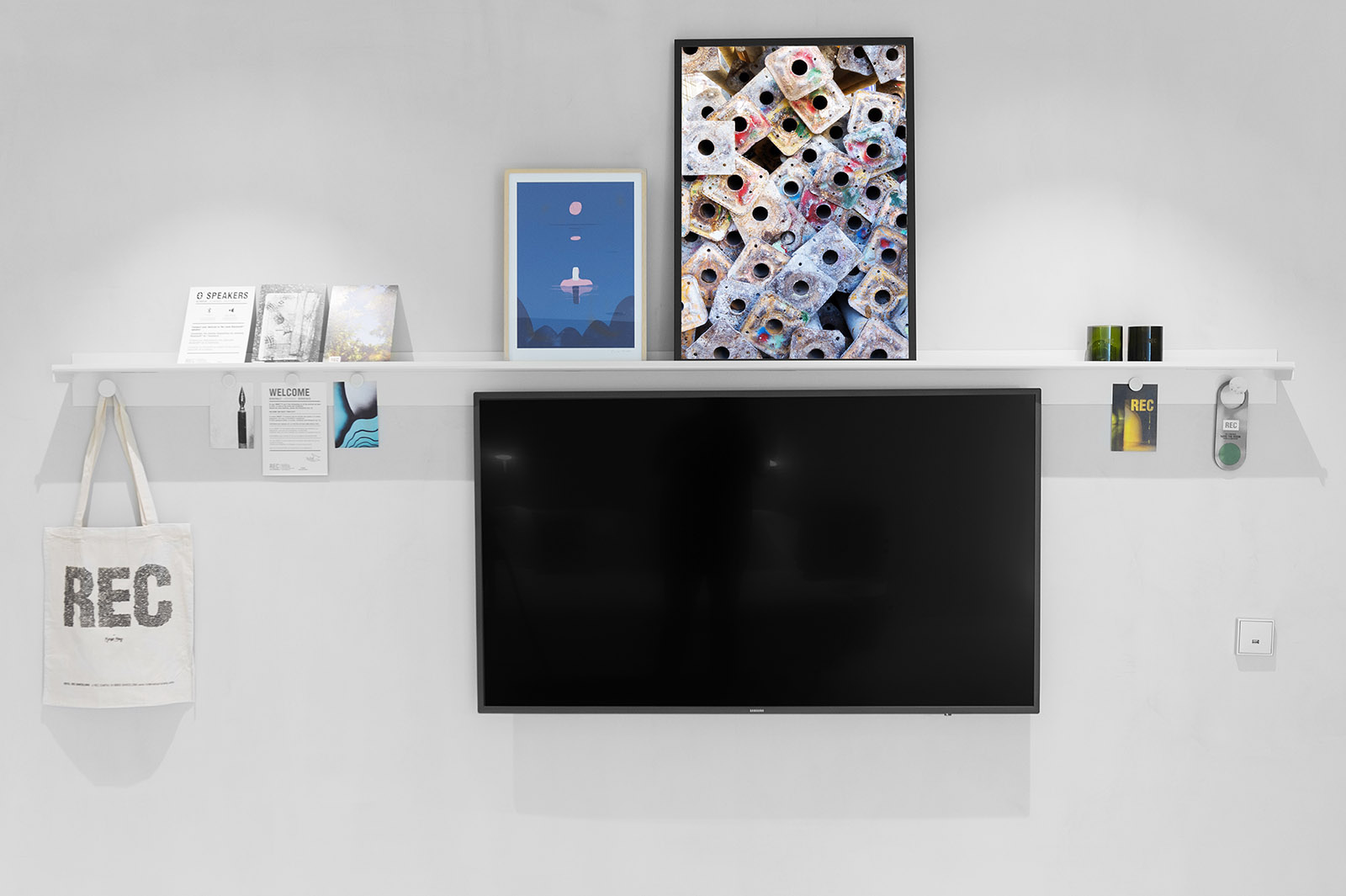 Se ve un televisor de pantalla plana montado en una pared blanca con estantes decorativos alrededor.